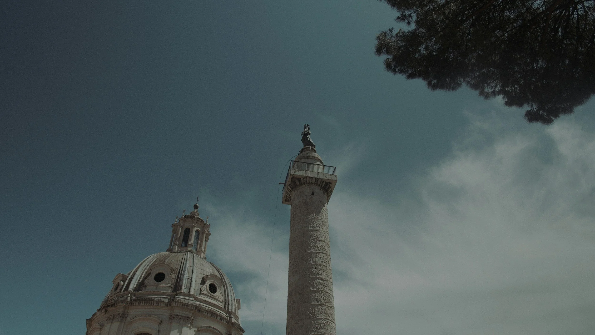 Vue d'une colonne avec une statue au sommet, à côté d'une structure circulaire avec un dôme.