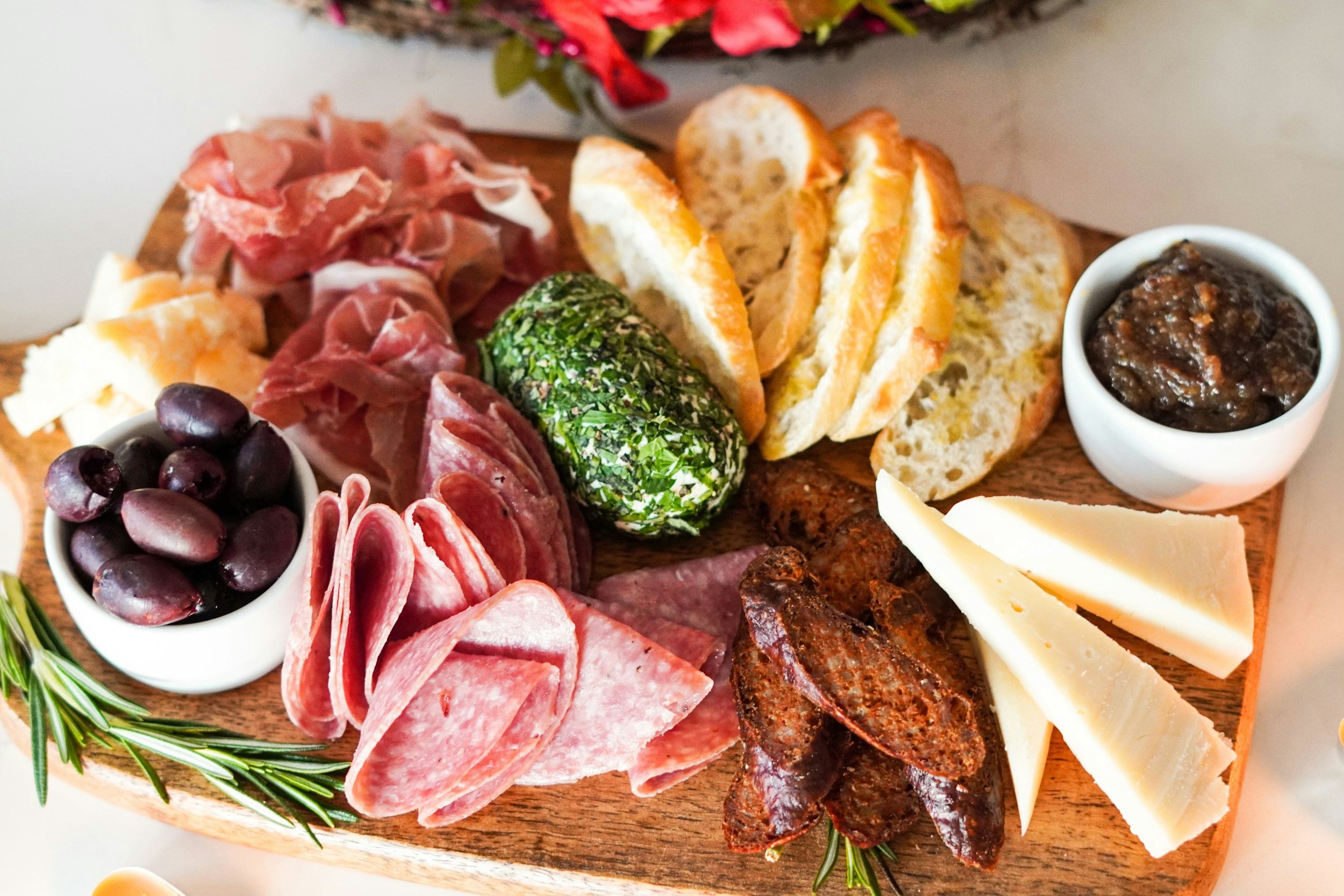Happy hour charcuterie board with meats, cheeses, olives, and sliced baguette.