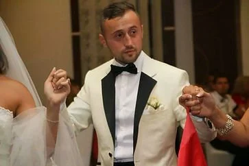 A man in a tuxedo holding hands with a woman in a wedding dress during a wedding celebration.