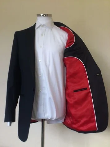 Partially open black blazer revealing a red and black golf bag inside.