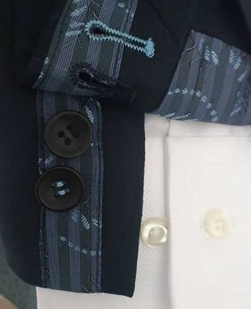 Close-up of a uniform with black buttons, a strip of fabric with a blue and gray pattern, and a white fabric background with buttons.