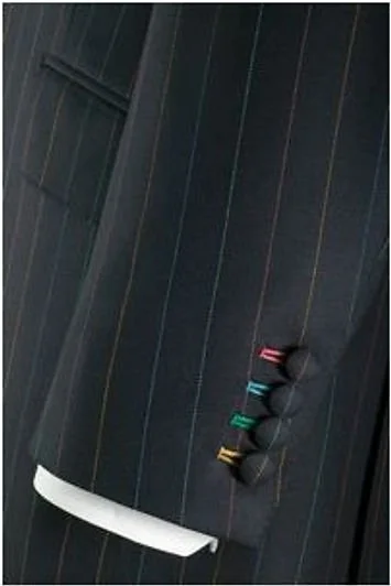 A close-up of a dark pinstripe suit with four colorful markers tucked into the chest pocket.