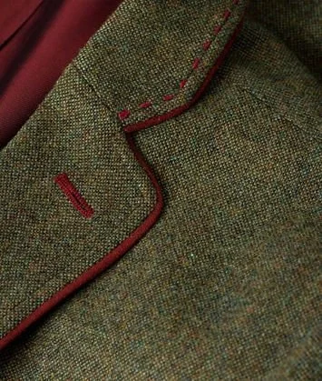 Close-up of a green tweed jacket with red piping and stitching.