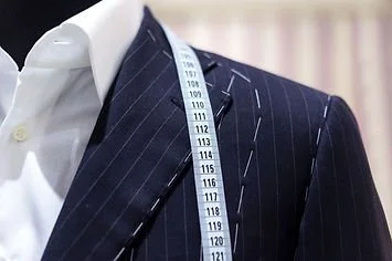 Close-up of a man's suit with a measuring tape draped over the shoulder.