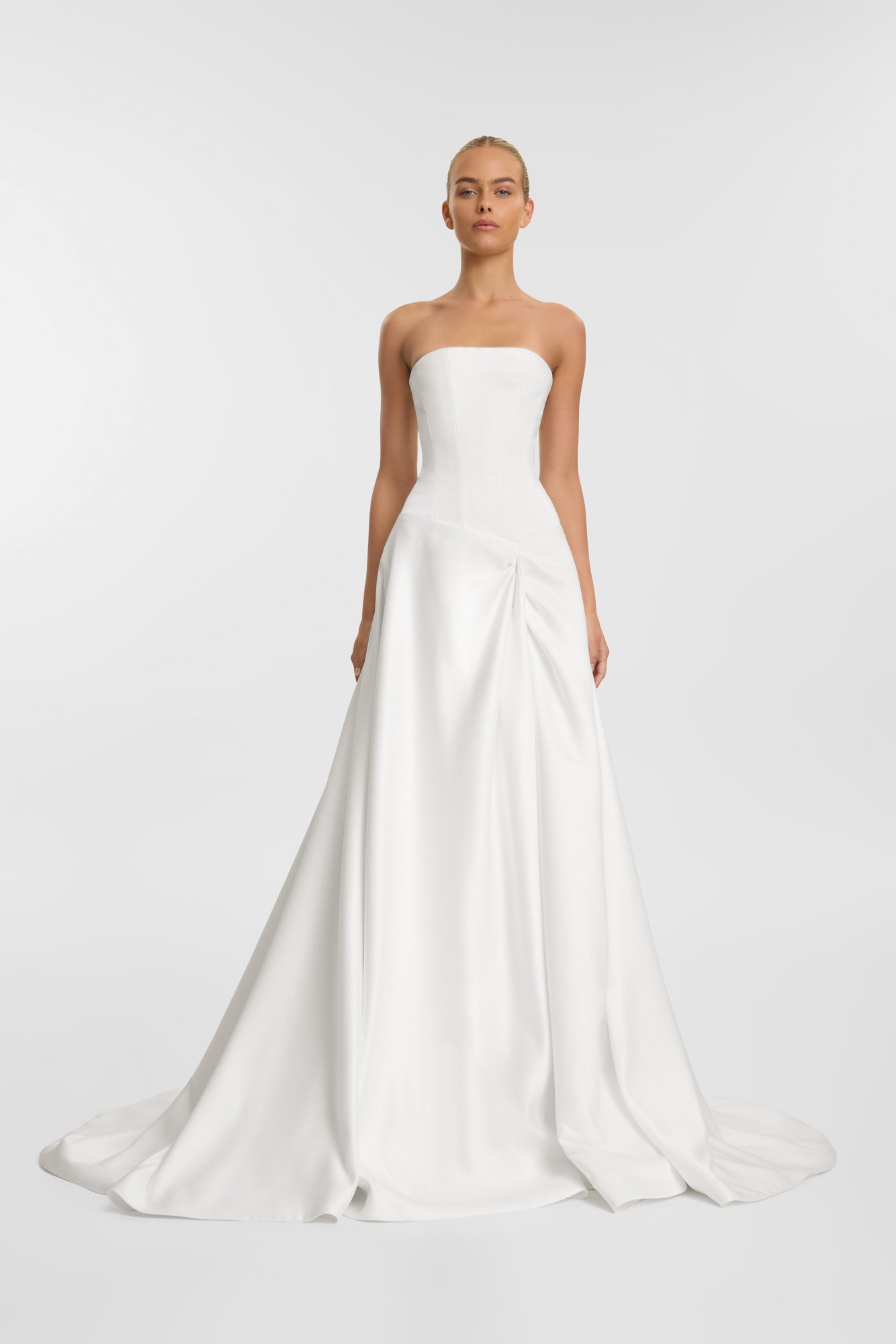 A woman wearing a strapless white wedding dress with a fitted bodice and a full skirt that flows to the floor.