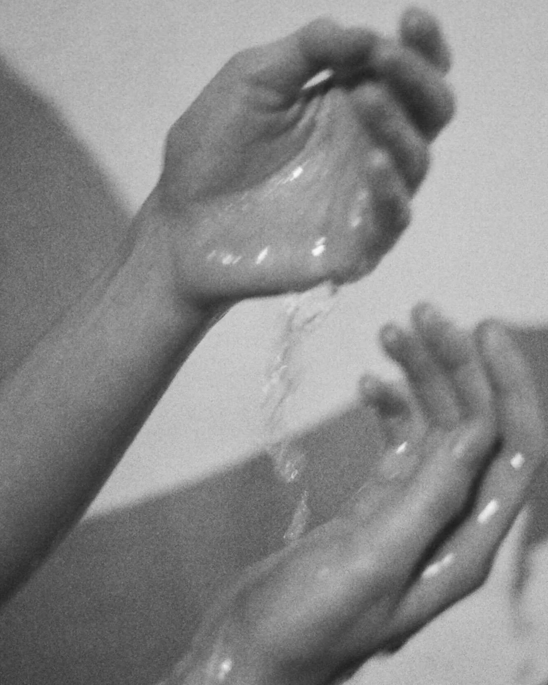 Hands with water pouring over them in black and white.