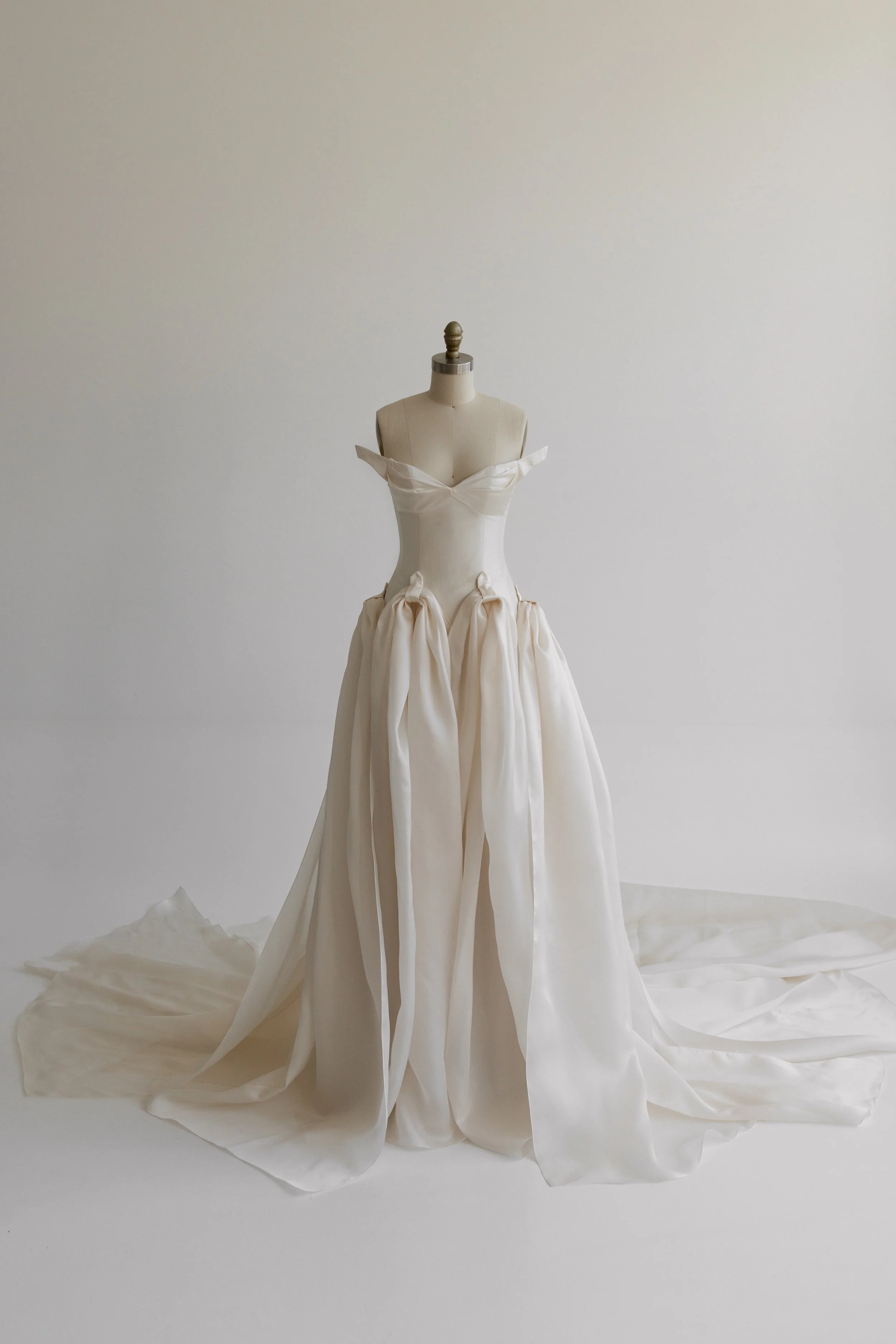 White wedding gown displayed on a mannequin against a plain background.