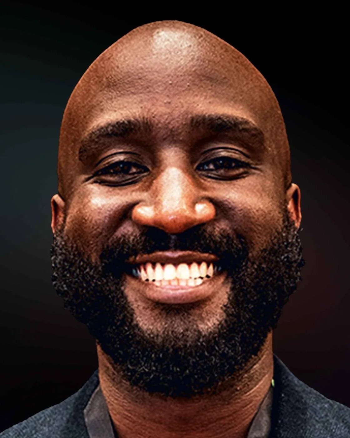 Image of Delany Odanga smiling with a closely shaved head, dark beard, and bright white teeth looking directly at the camera.