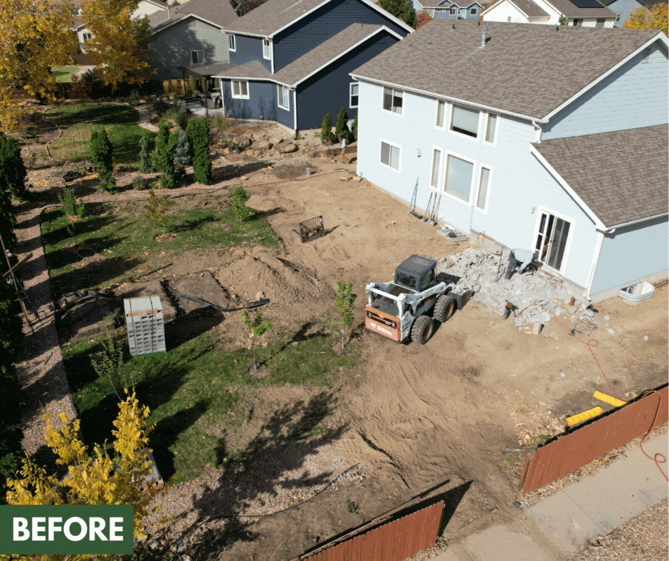 An aerial view of a backyard undergoing renovation with dirt and construction equipment, including a small skid steer loader, and a partially built or renovated house with a gray roof; adjacent house is painted blue. The yard contains small trees, shrubs, and a deck in the background. The image is marked with a 'BEFORE' label in the bottom left corner.
