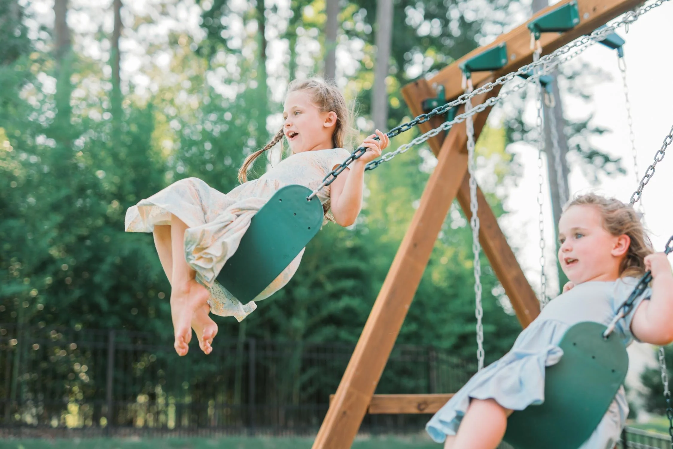 Two girls swinging together on a swing set during a playful family photography session in Raleigh–Durham.
