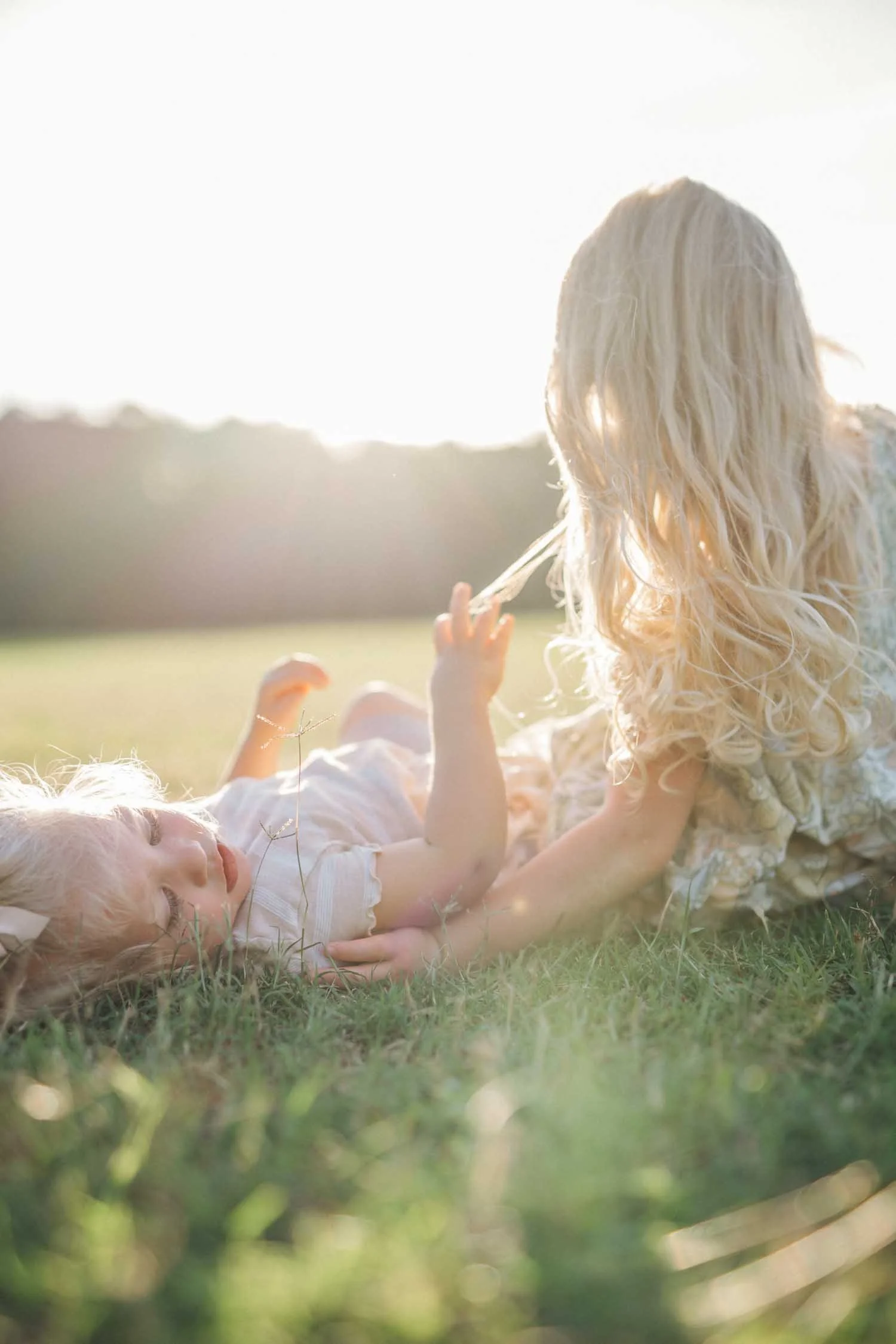 Two toddlers lying in the grass during a park family photography session near Cary, NC.