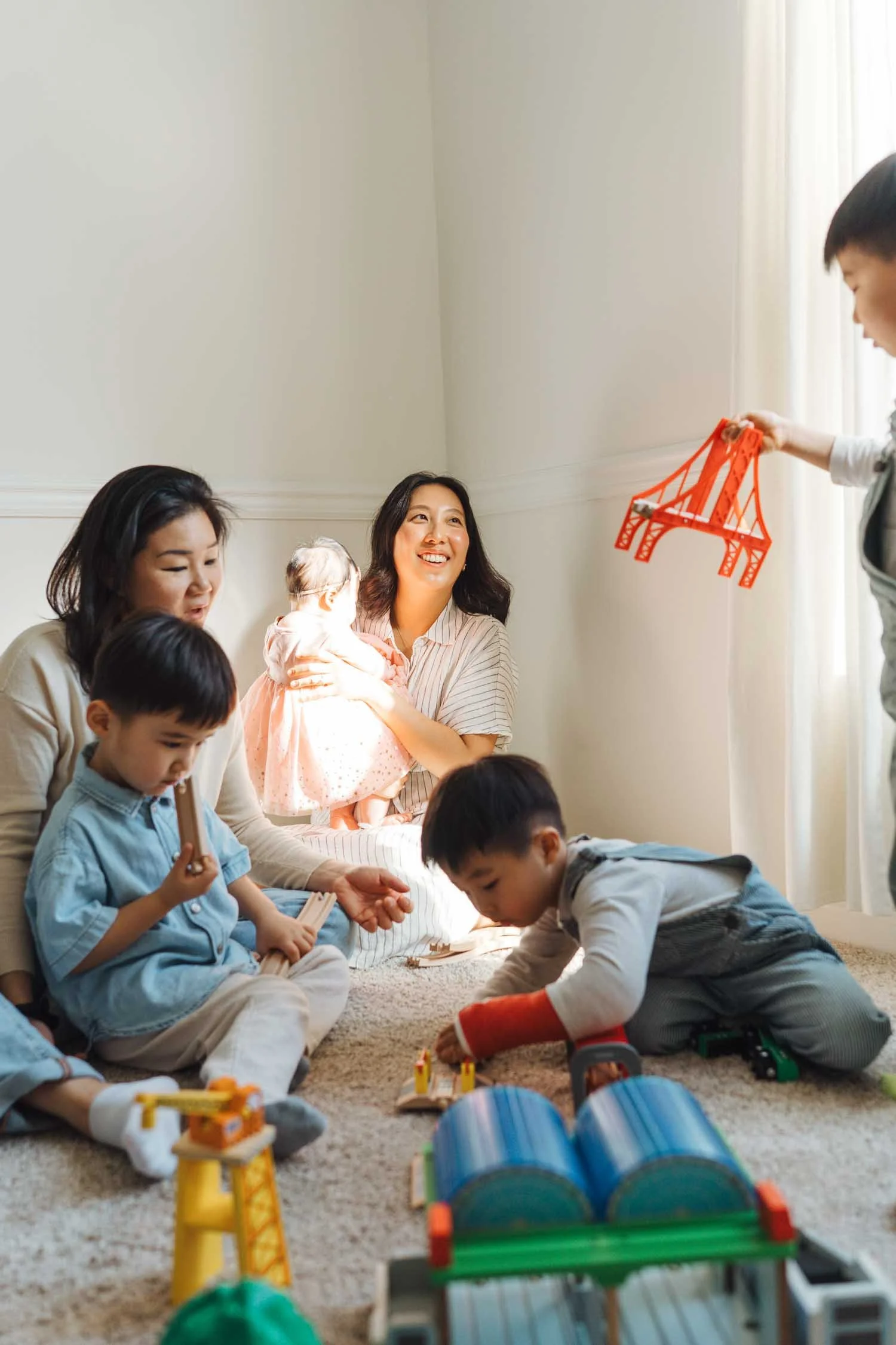 Parents sitting on the floor playing with toys alongside their three children at home during a documentary-style family photography session in Raleigh, North Carolina.