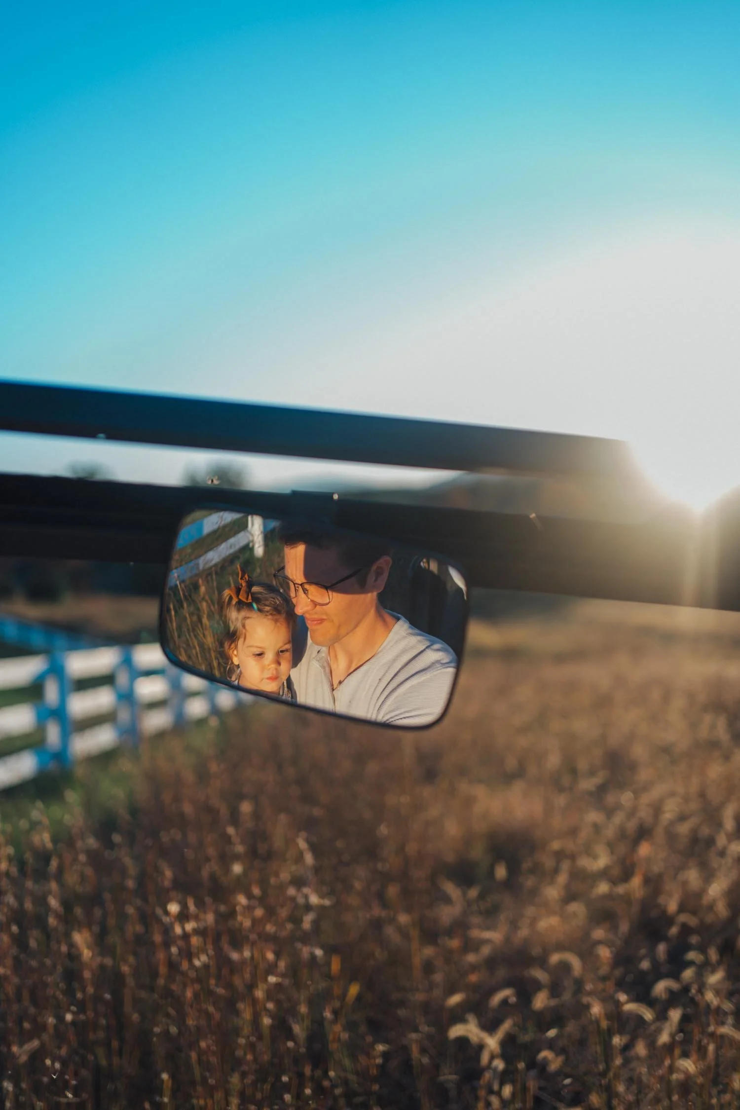 Rear-view mirror reflection showing a father and daughter hugging during a family photography session by Autumn Brooke Photography.