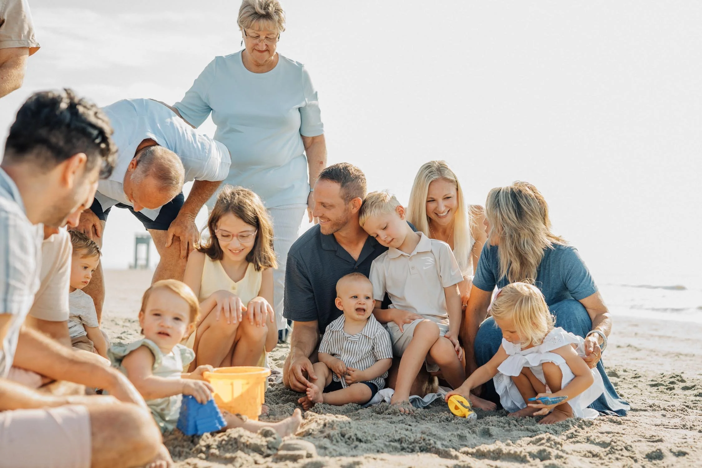 Large family playing together in the sand at the beach during a lifestyle family photography session in North Carolina.