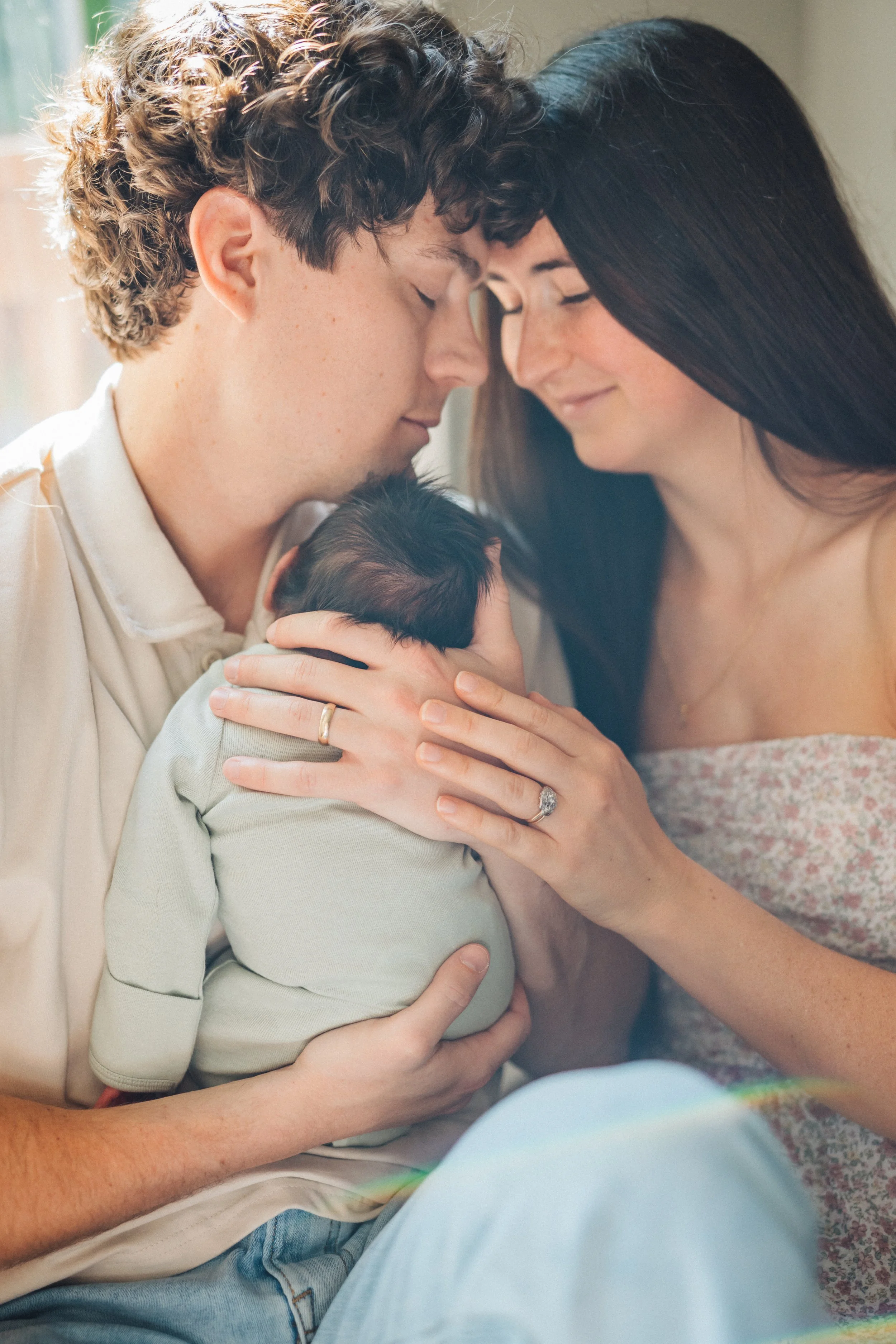 mom and dad touching heads and holding newborn baby Raleigh, NC Family Photography