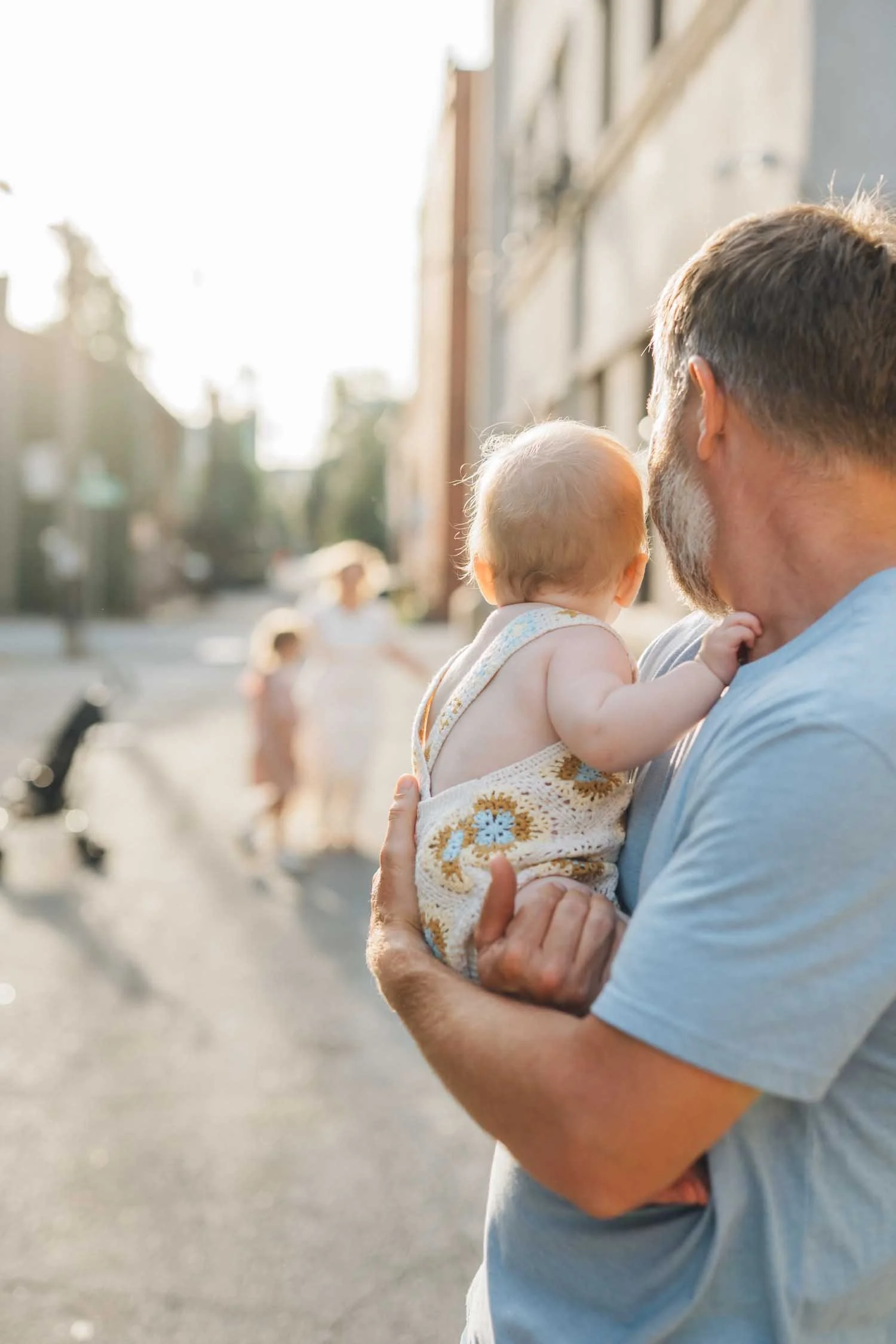 Father holding his baby outside in a downtown setting during a Locals family photography session in Raleigh, NC.