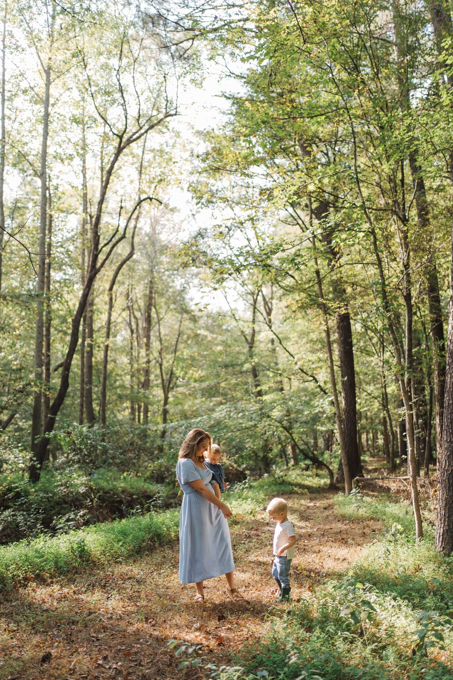 Mother walking through the forest with her young son during a lifestyle family photography session in Raleigh–Durham.