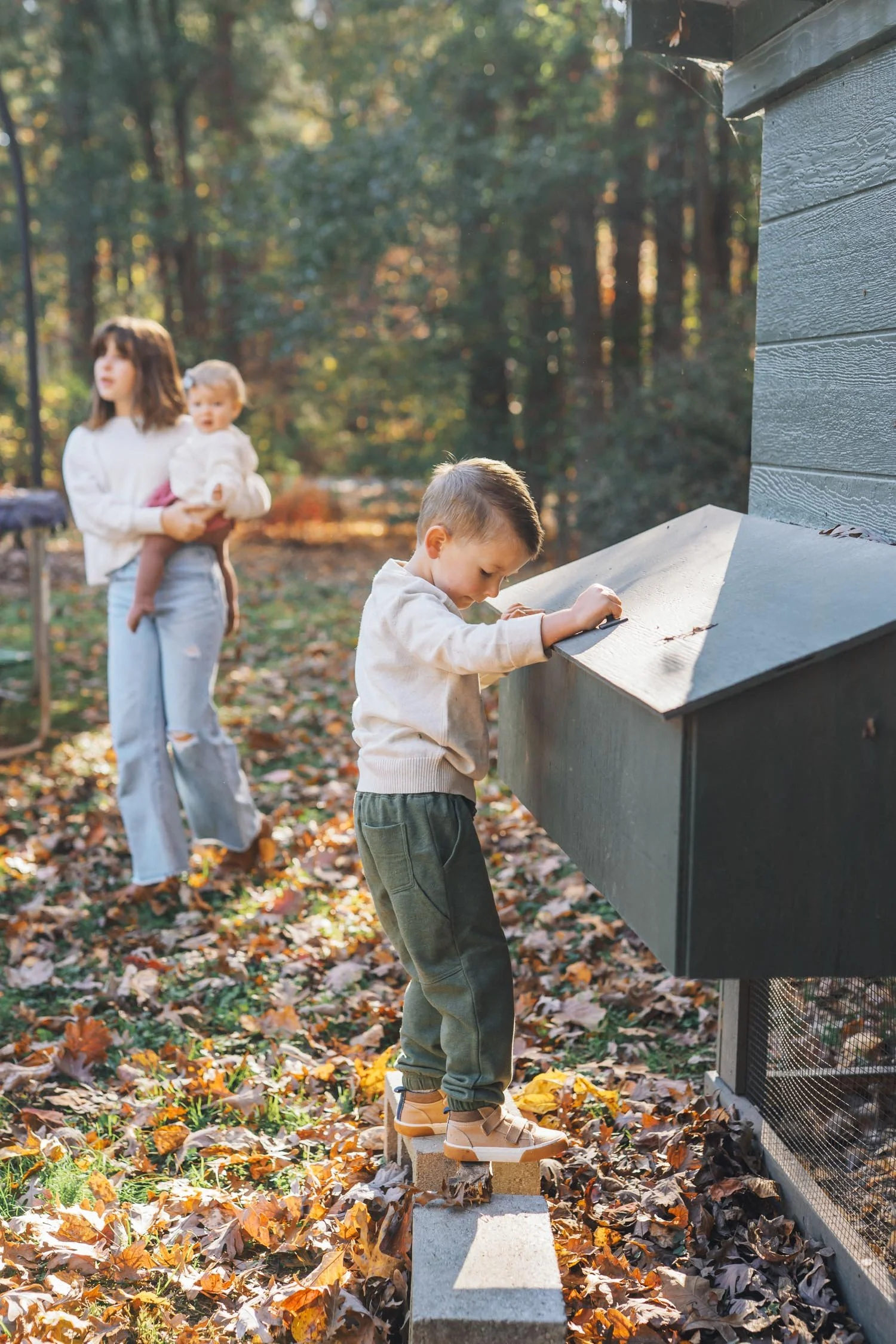 Mother and son playing together outside near a chicken coop during an at-home family photography session in Raleigh–Durham.