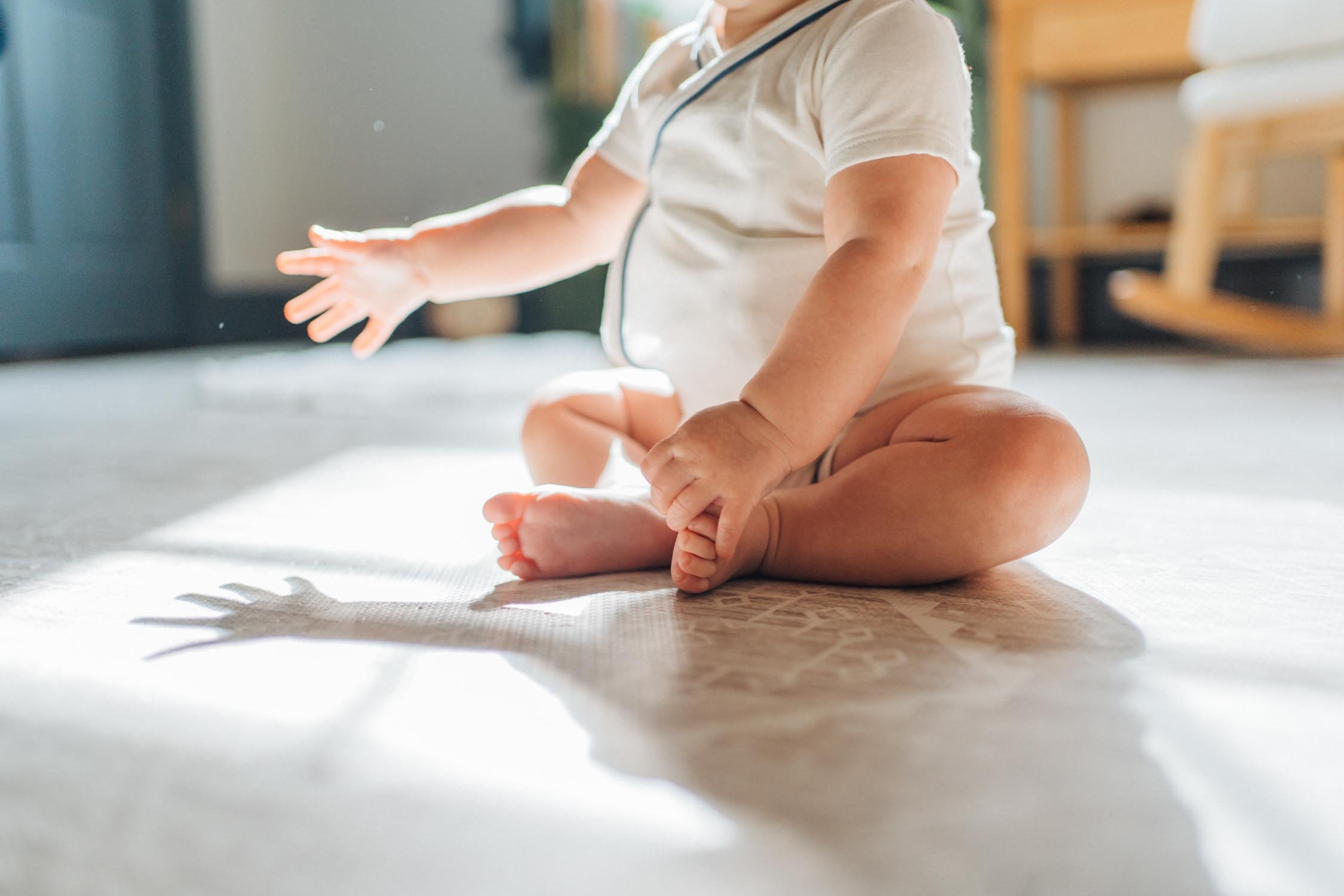 Close-up of a baby sitting on the couch during a candid in-home family photography session in Raleigh–Durham.