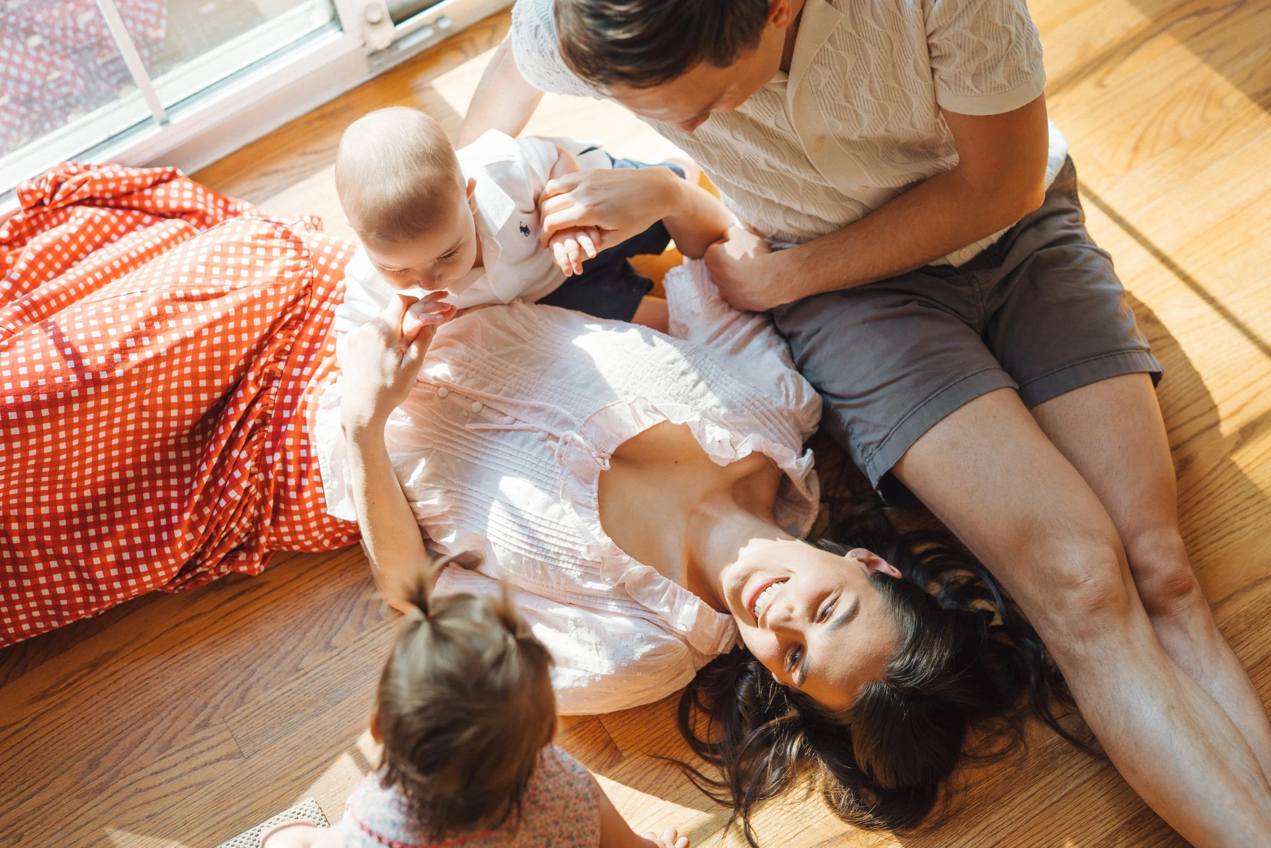 family of four laying on their floor cuddling and smiling at their home in Raleigh, North Carolina for natural family photos