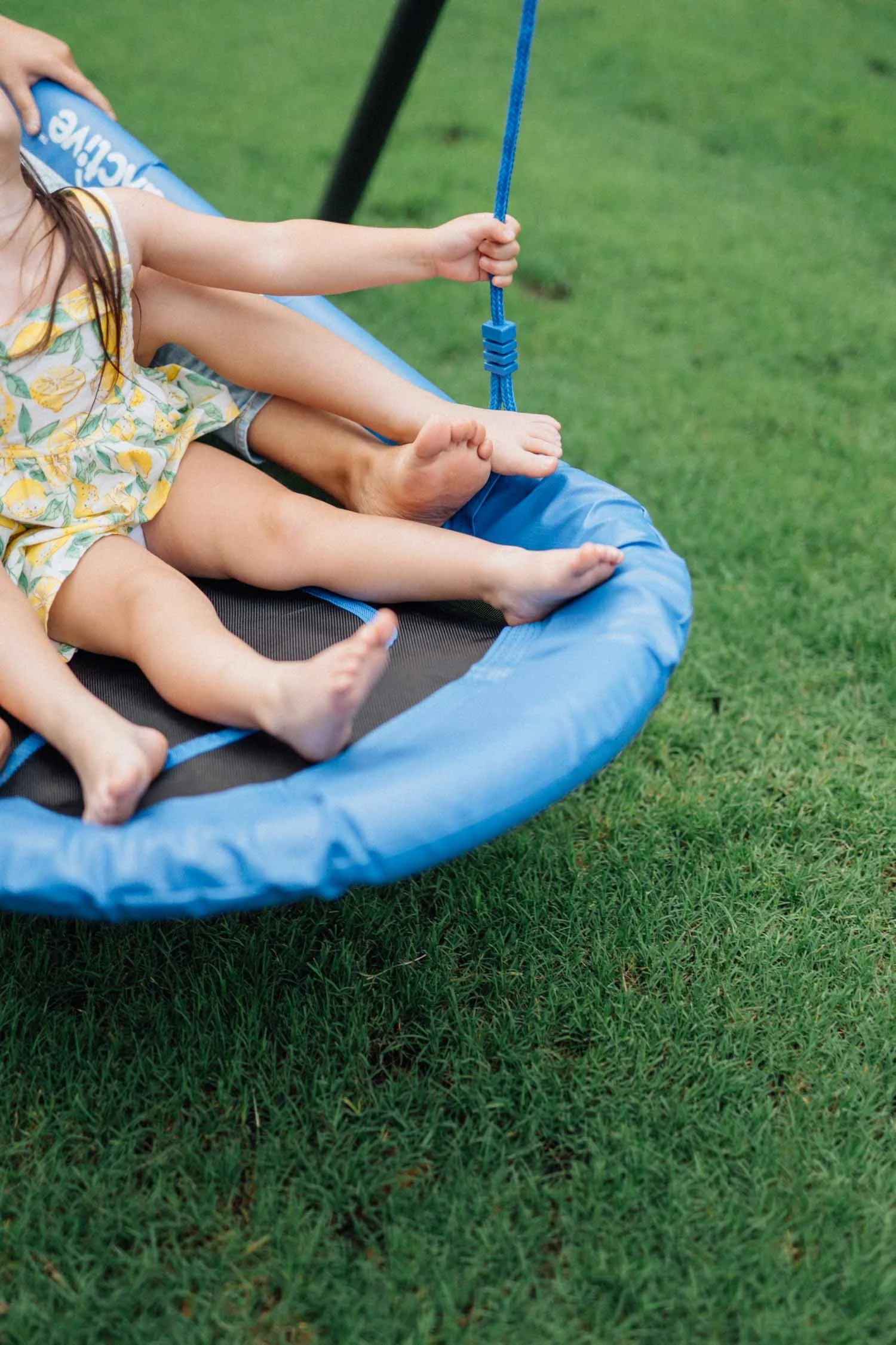 Detail shot of children’s feet resting on a trampoline swing during a playful family photography session.