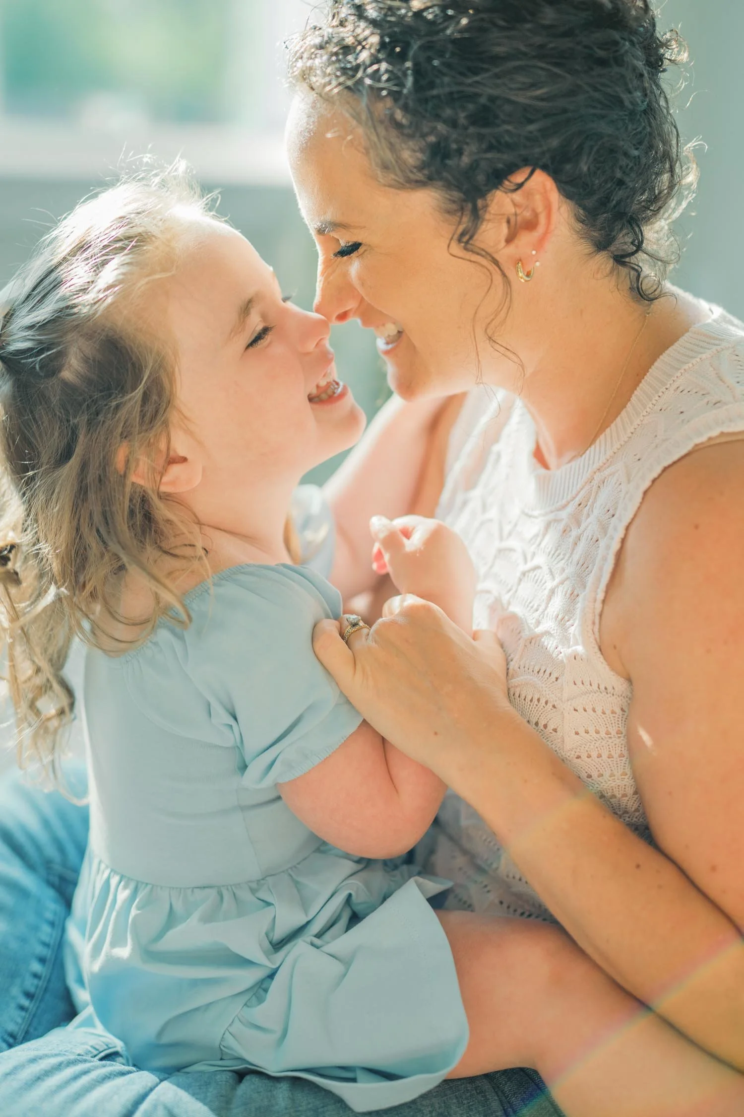 Mother holding her daughter close, touching noses and laughing during a backyard family photography session with Autumn Brooke Photography in Raleigh, NC.