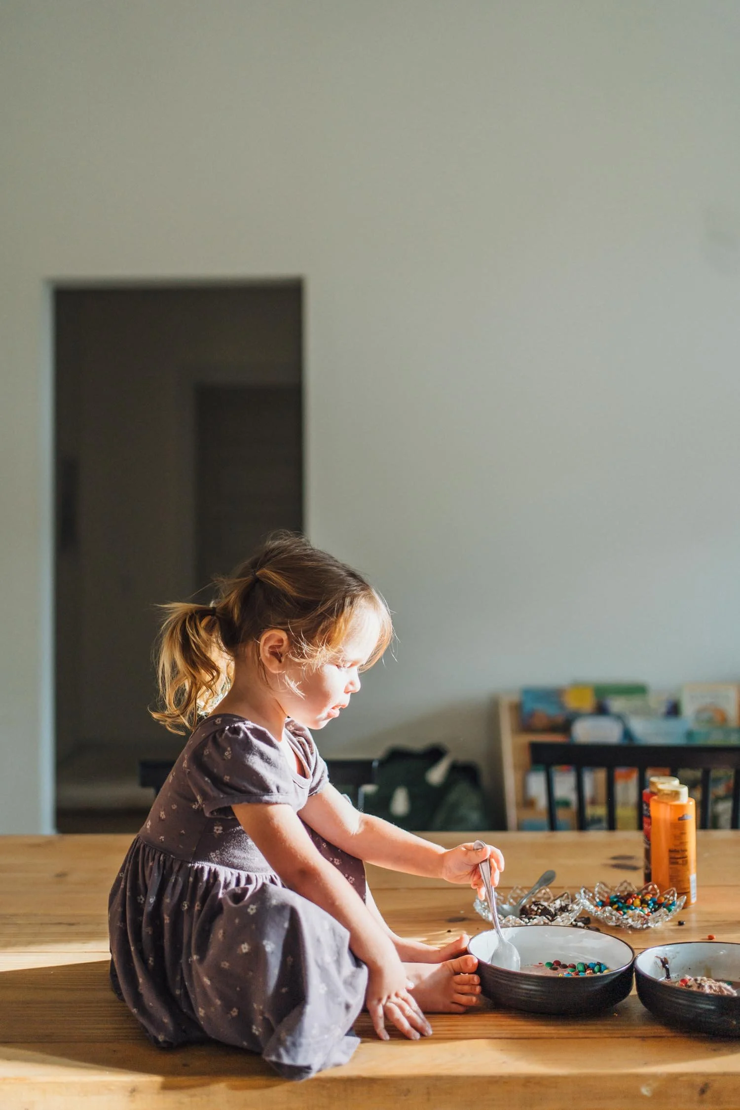 Toddler eating cereal while sitting at the dining table during a candid family photography session at home.