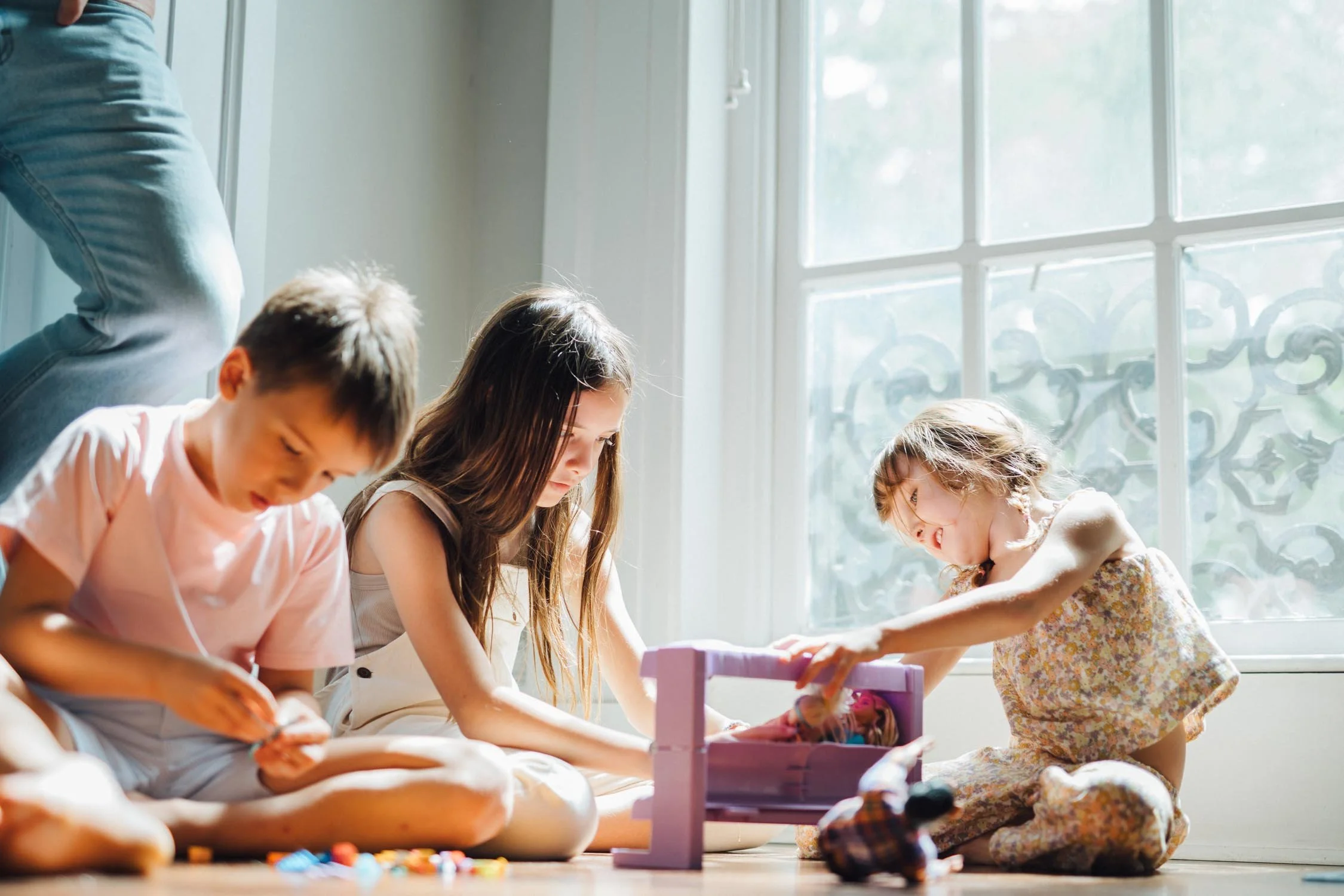 Three young children building a toy together on the floor of their home during a natural family photography session in Raleigh, NC.