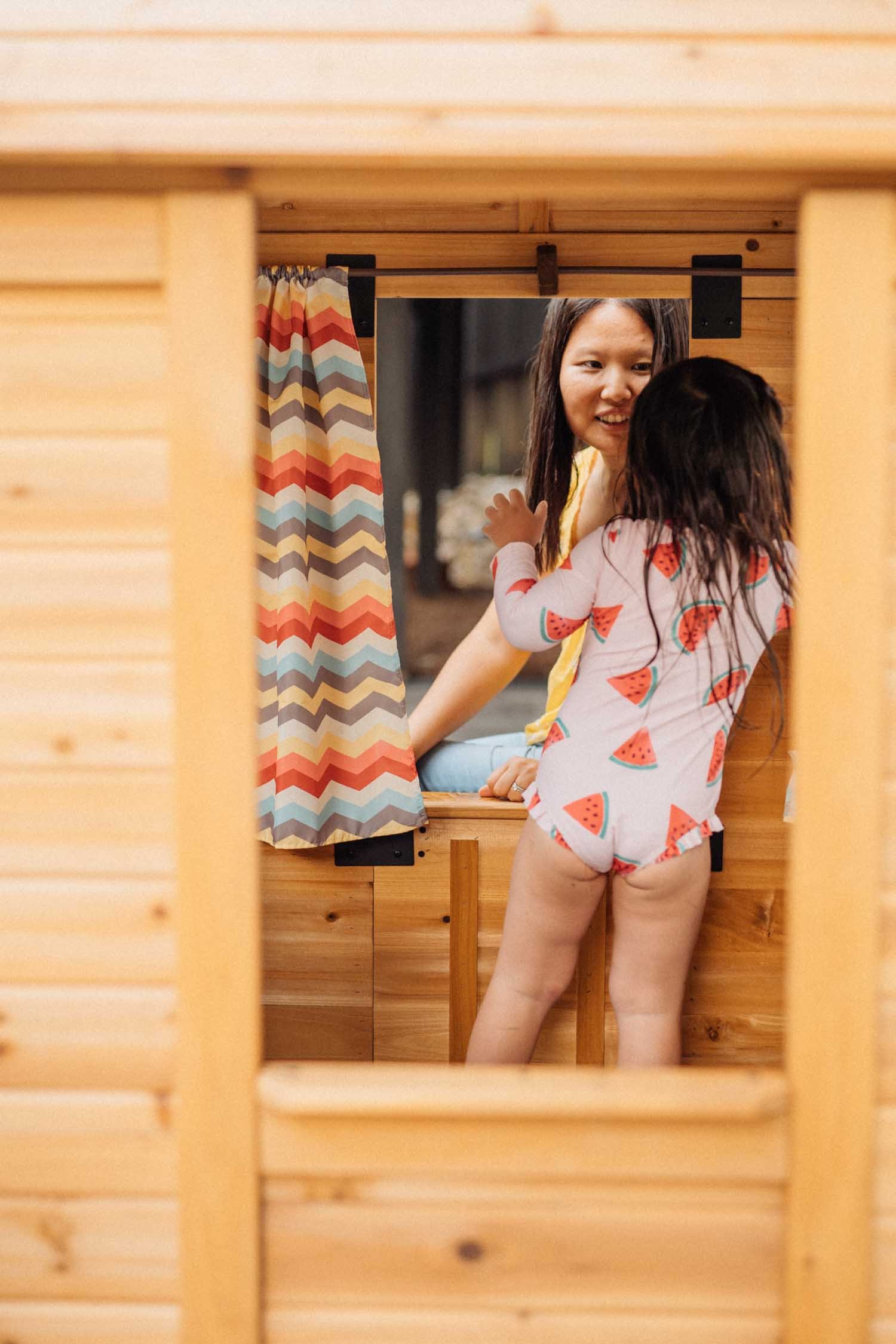 Mother and daughter playing together in a pretend playhouse during a backyard family photography session in Raleigh, North Carolina.