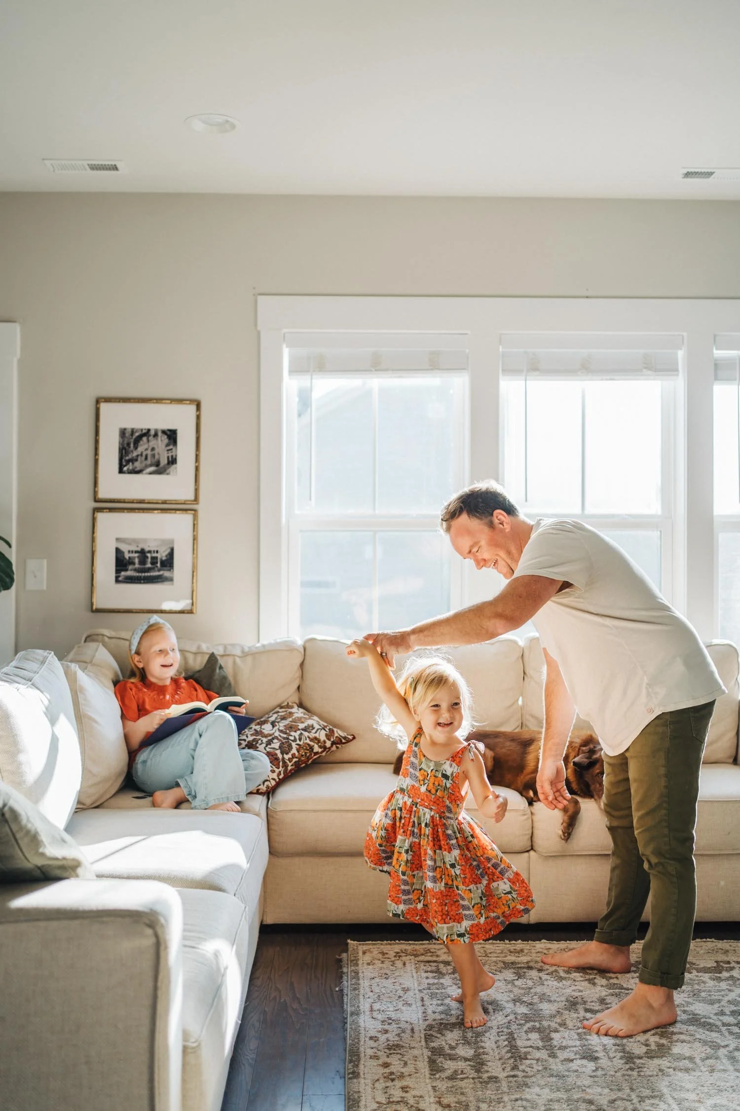 Father twirling his toddler daughter in a dress inside their living room during an in-home family photography session in Raleigh, NC.