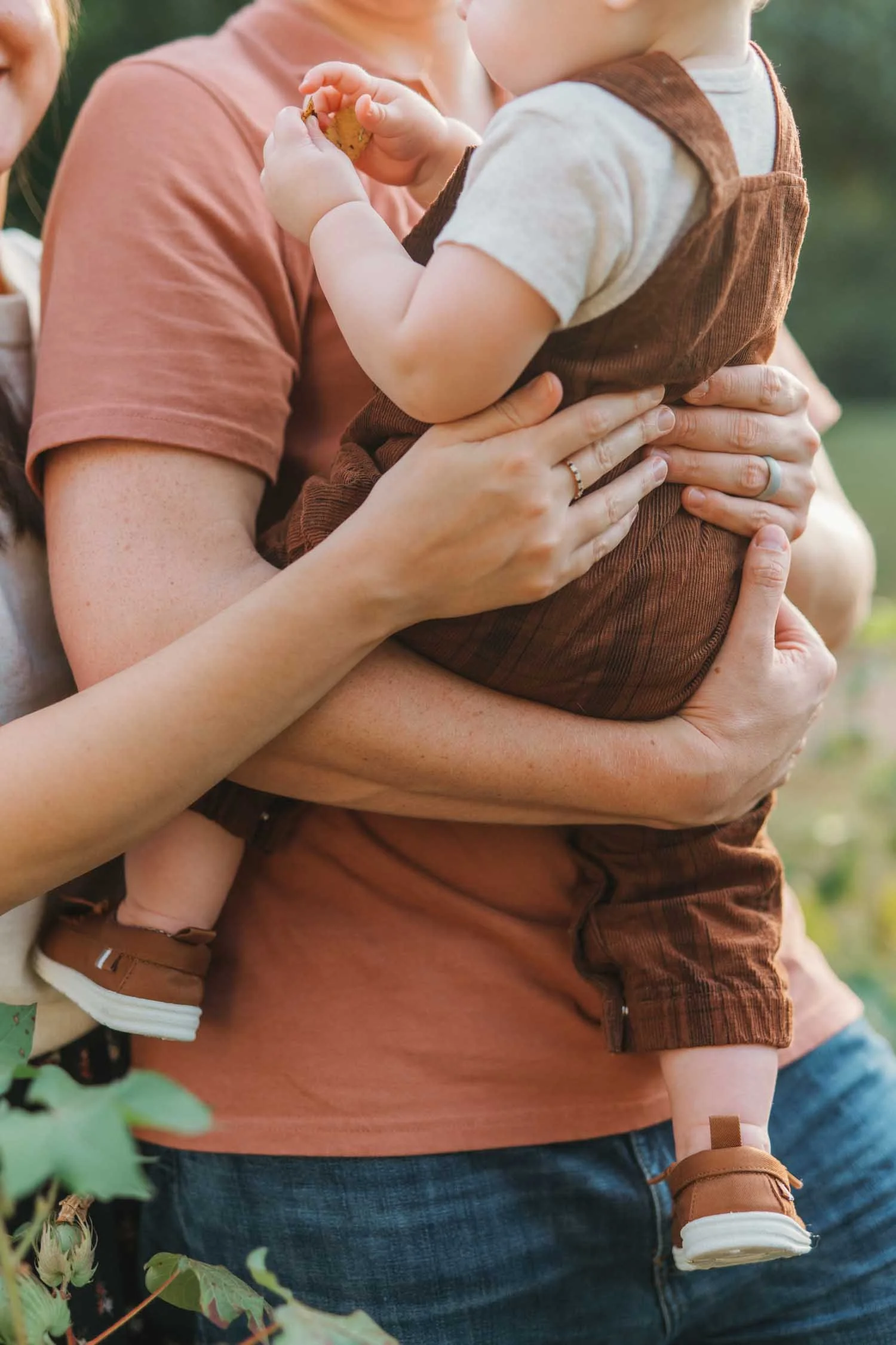 Close-up of a father holding his toddler son outdoors during a natural family photography session by Autumn Brooke Photography.