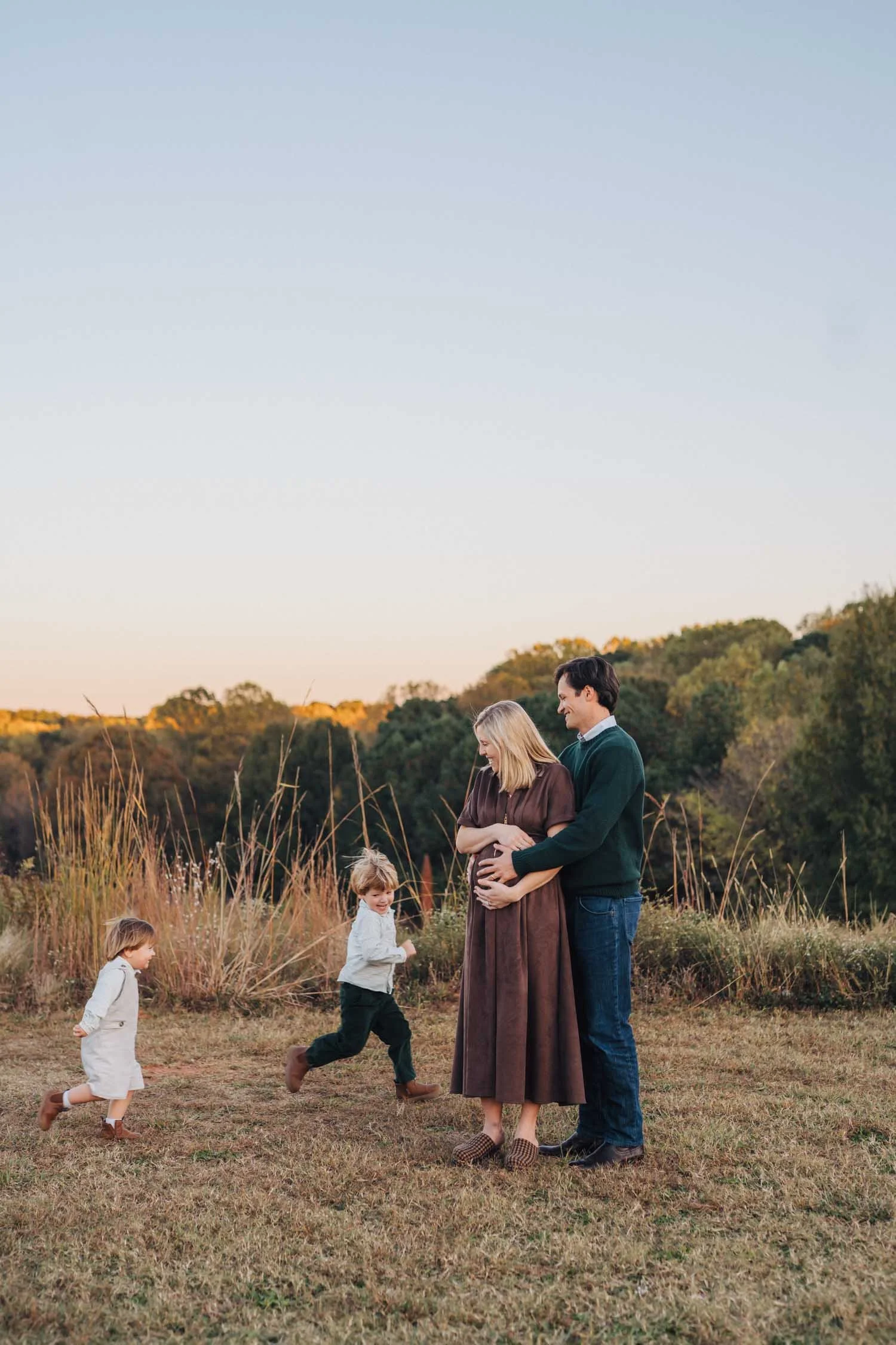 Parents watching their children run and play freely in a park during a lifestyle family photography session in Raleigh, NC.