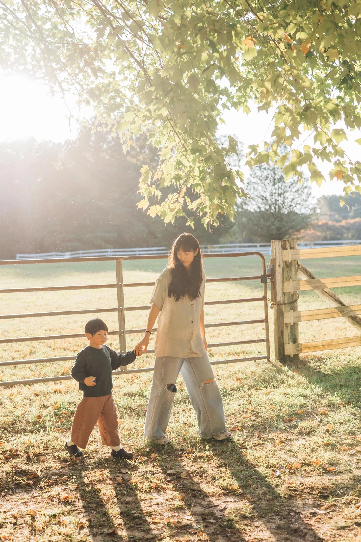 Mother and son walking together through the yard at golden hour during a family photography session in Raleigh–Durham.