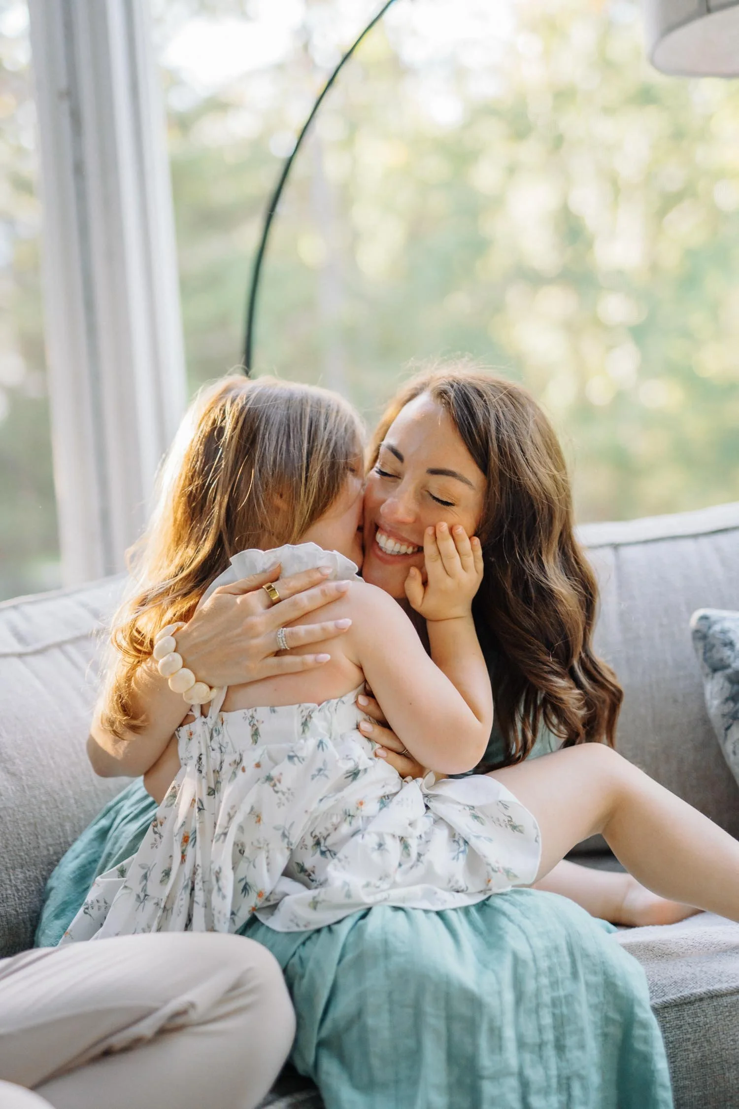 Mother hugging her daughter on her lap at home during a relaxed family photography session in Raleigh, North Carolina.
