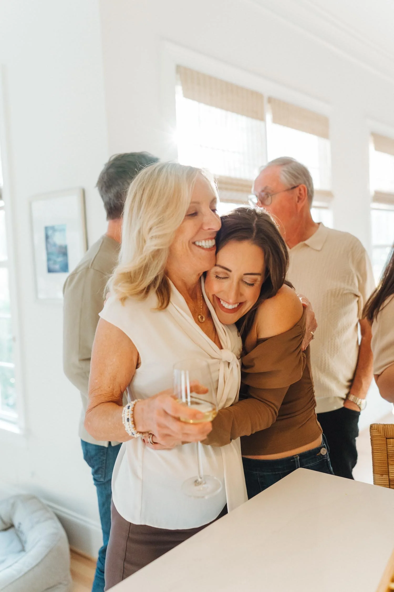 Adult daughter hugging her mother in the kitchen, surrounded by family during a multi-generational family photography session in Wake Forest, NC.