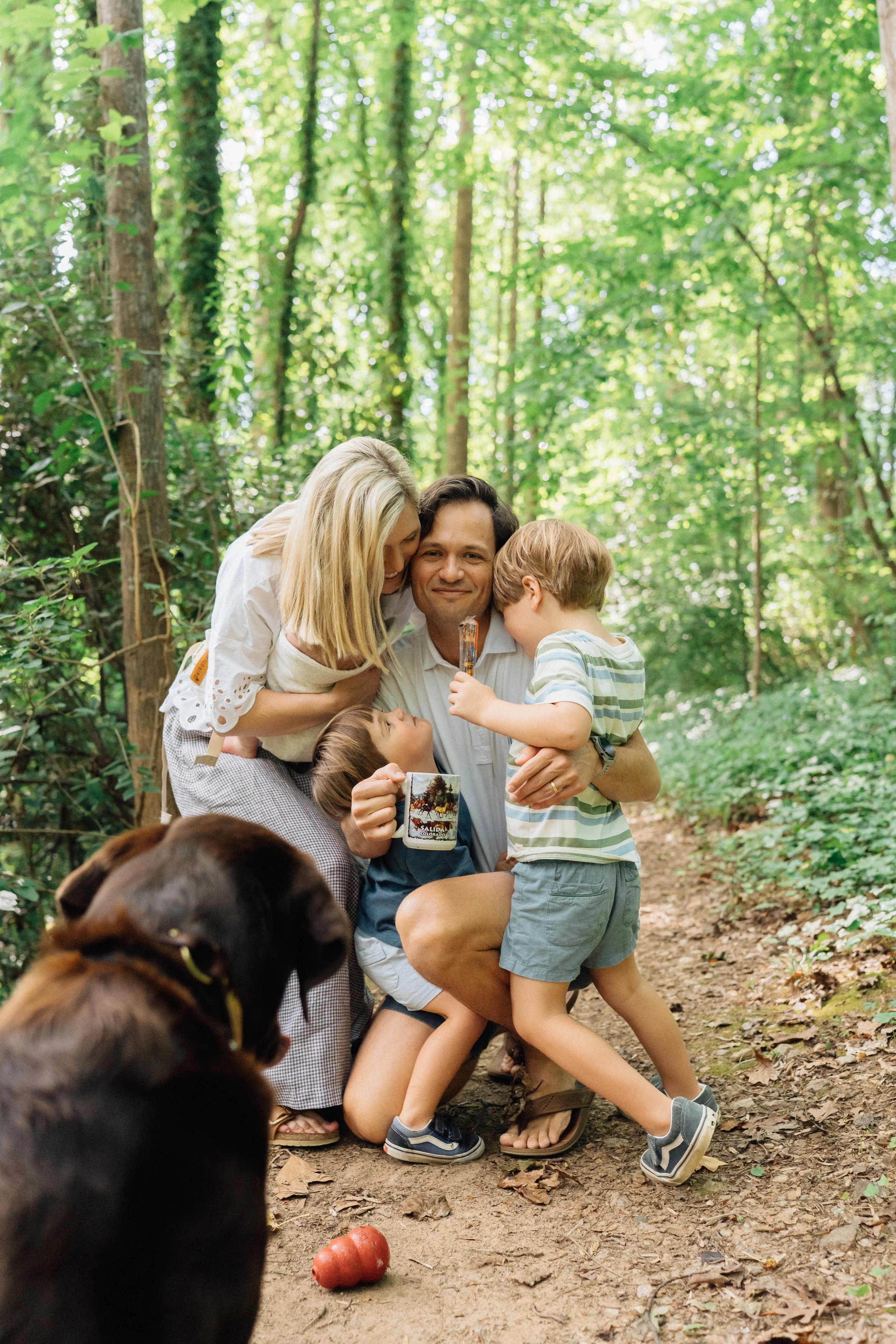 Family at home in Raleigh NC on a trail hugging dad with coffee in his hand for Lifestyle Family Photos