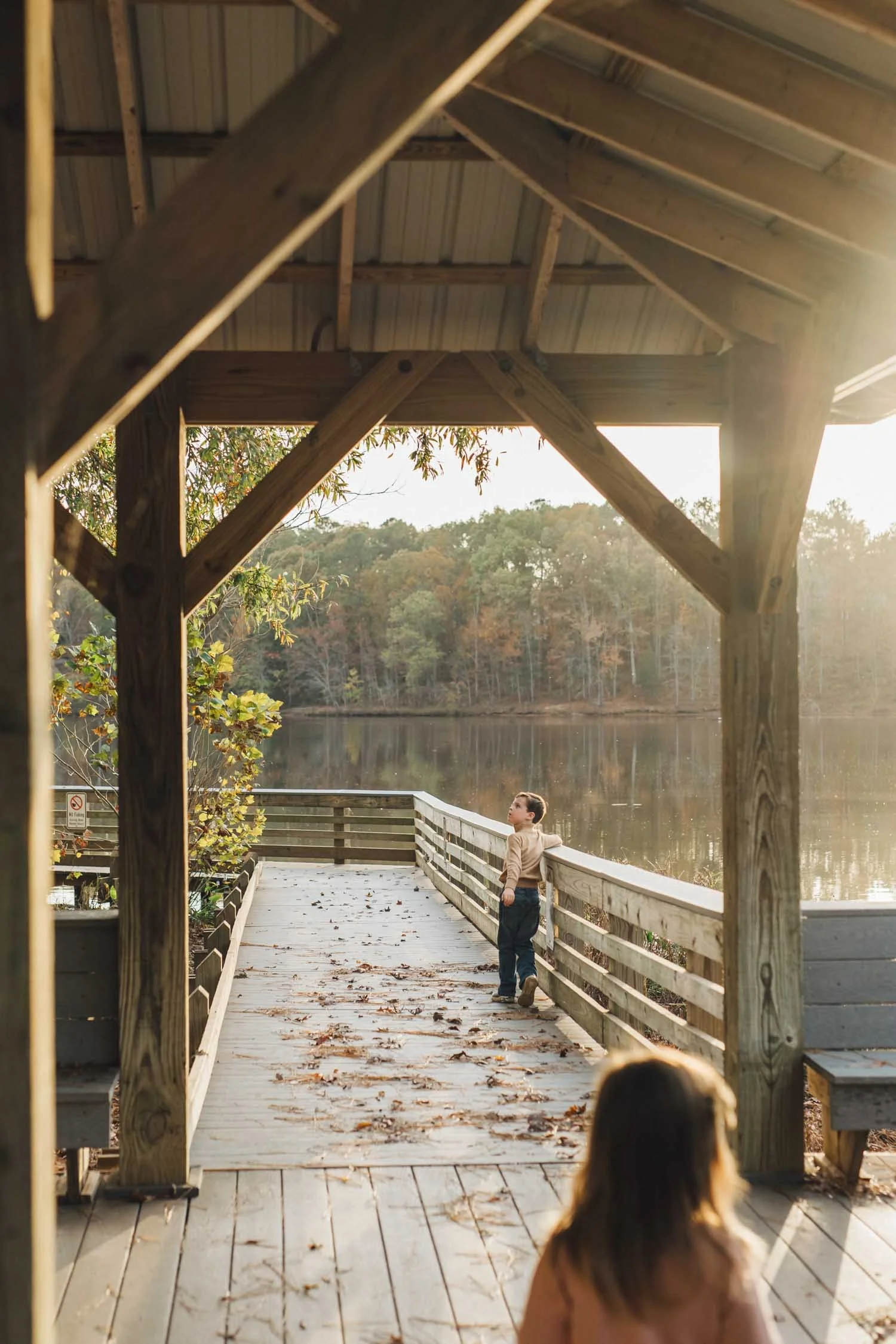 Child walking down a pier surrounded by trees during a quiet family photography moment in North Carolina.