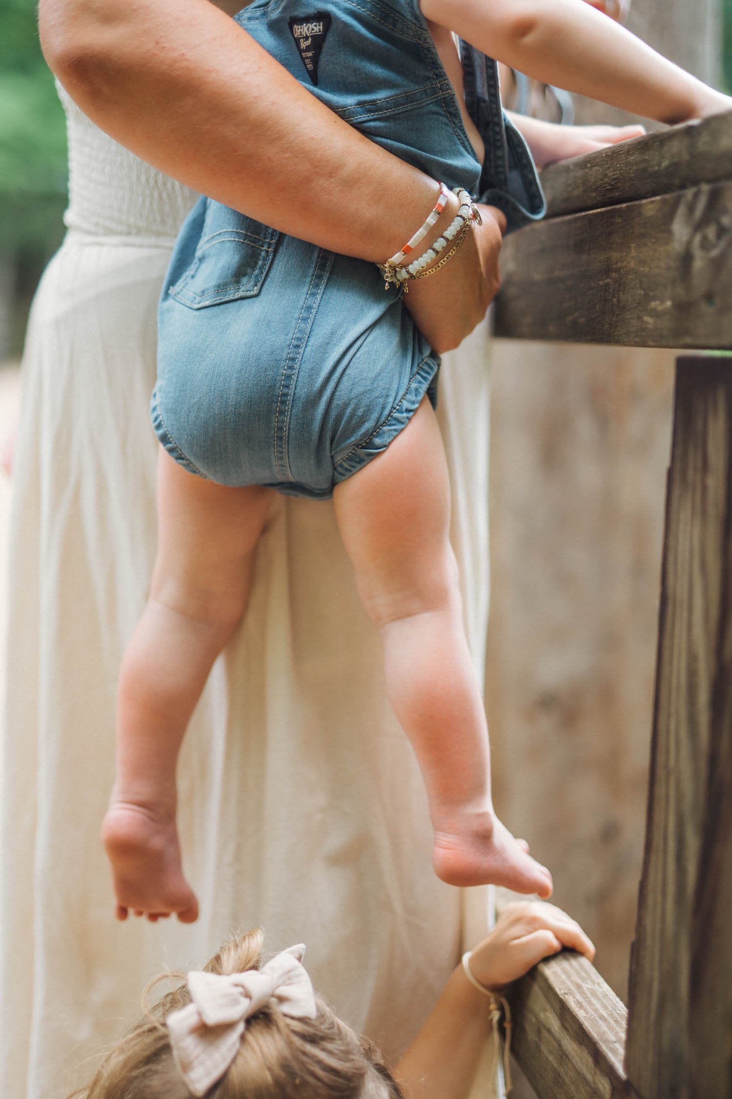 Close-up of a woman holding her baby beside an outdoor railing during a lifestyle family photography session by a Raleigh, NC family photographer.