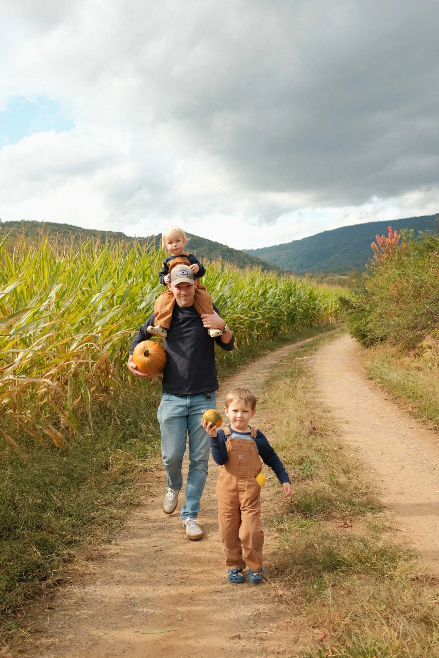 Autumn's husband and sons, in a field during a candid lifestyle family photo session.