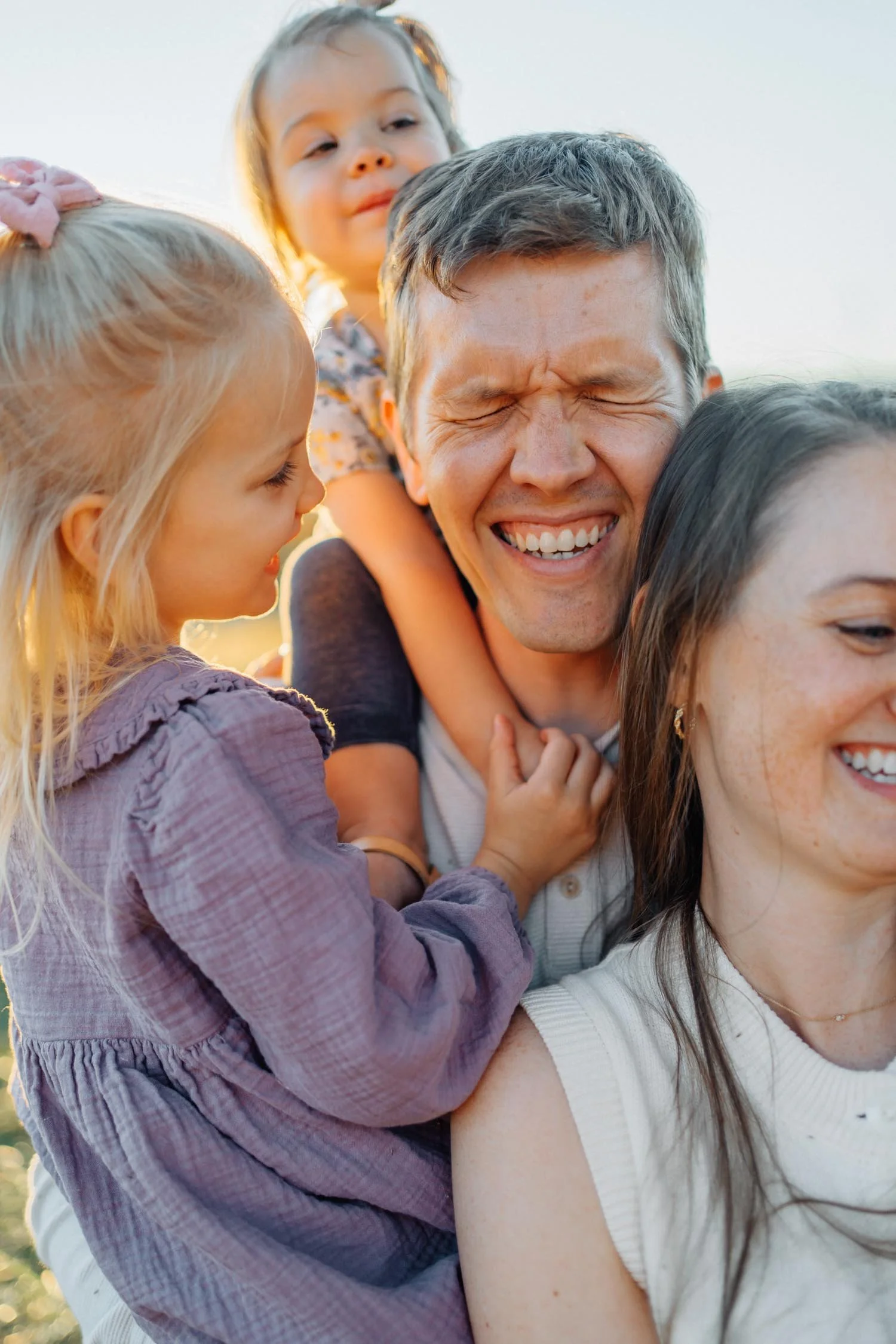 Two parents standing together with their children on their shoulders during a family photography session in Raleigh, North Carolina.