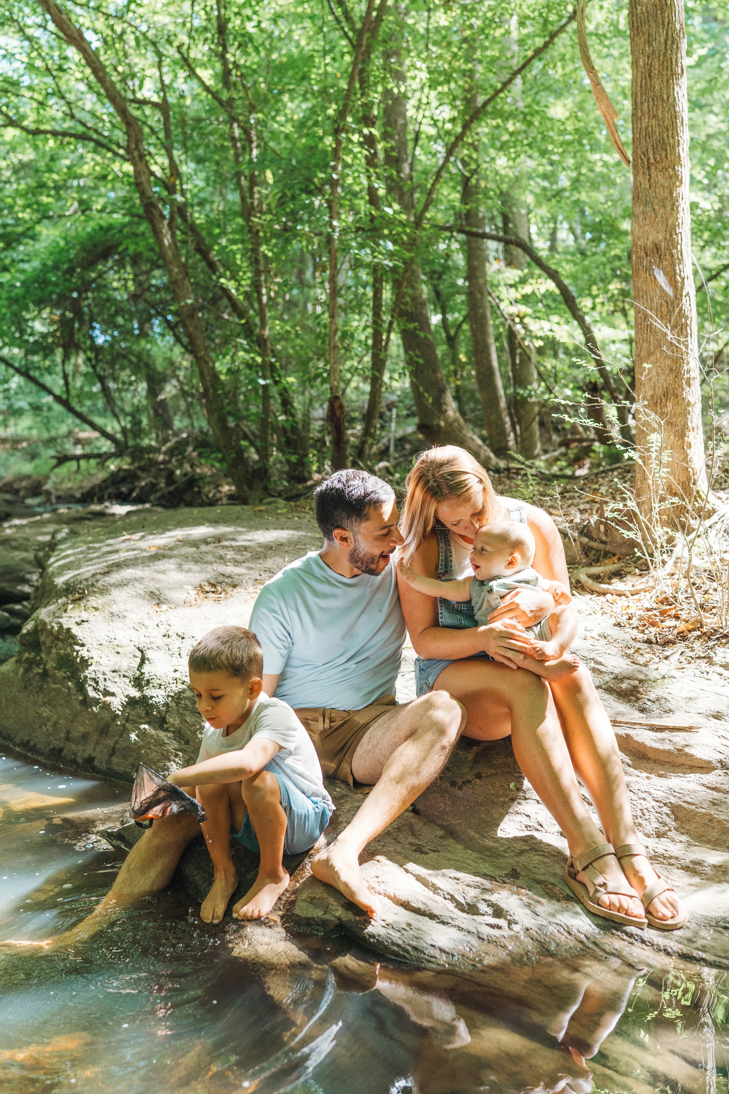 Family with two young kids playing in a creek at Durant Nature Preserve for storytelling family photos in Raleigh, NC