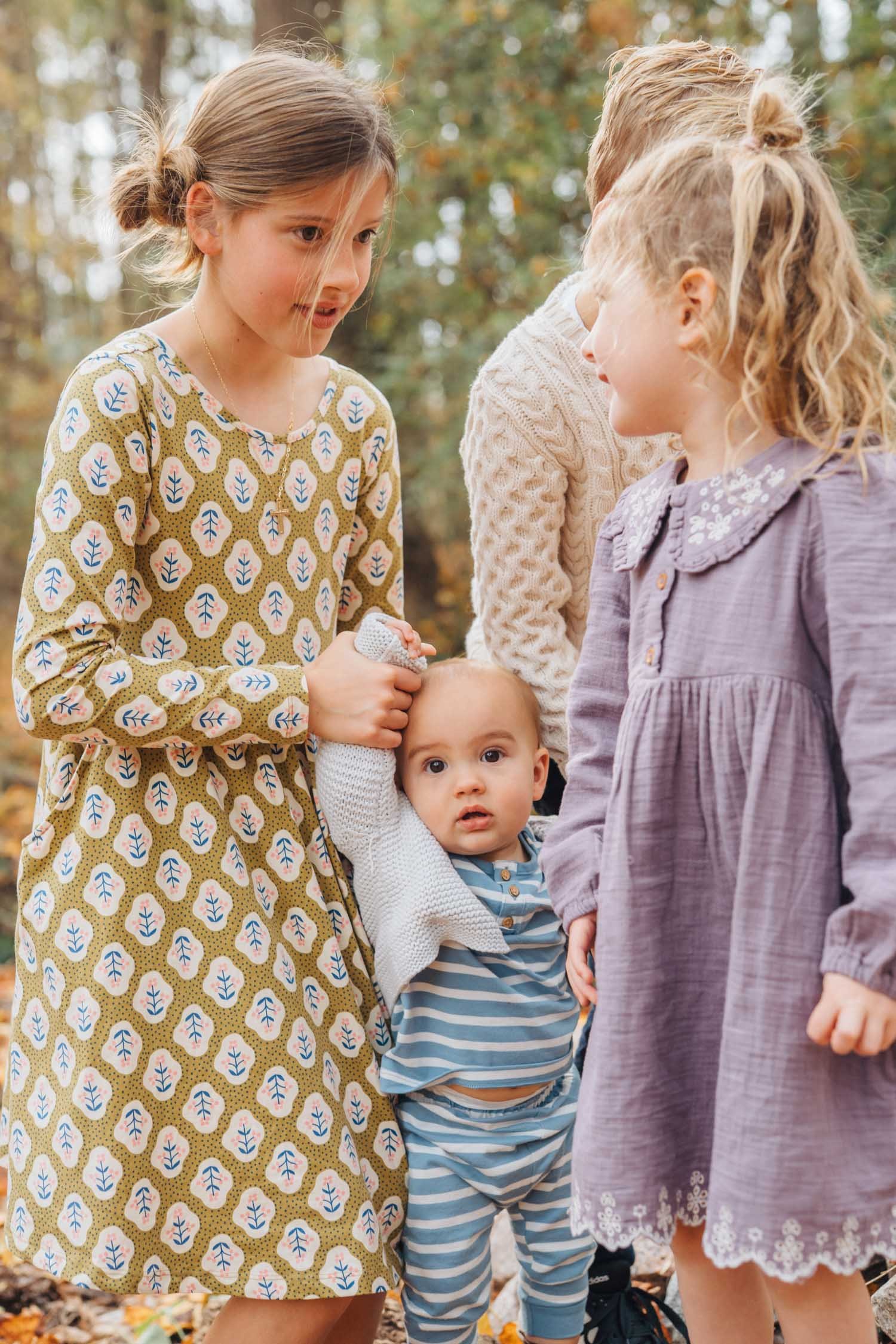 Three children holding their baby sibling up together outdoors during a joyful family photography session in Raleigh, North Carolina.