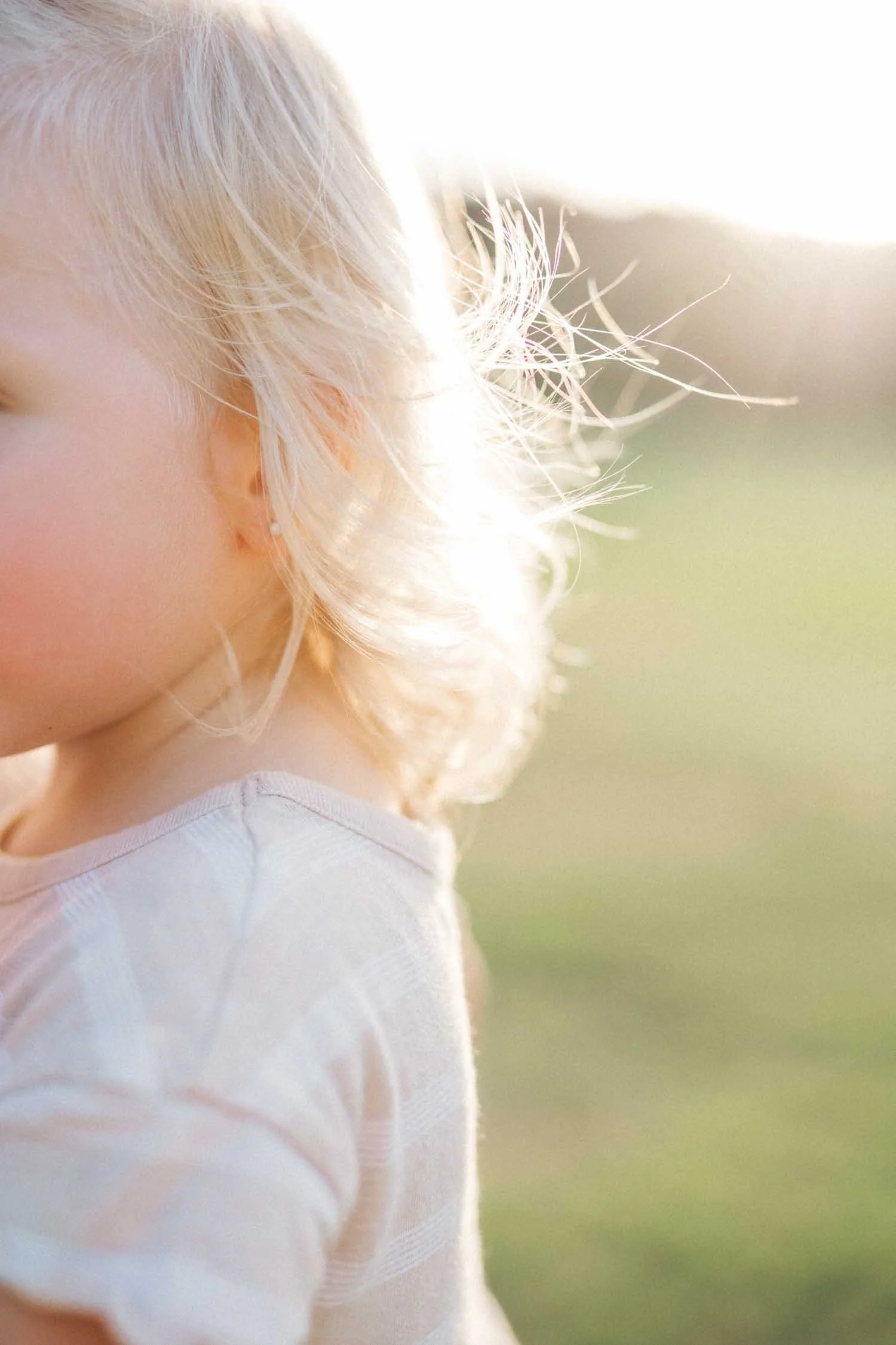 Close-up of a little girl’s hair blowing in the wind at the park during a family photography session in Raleigh, NC.