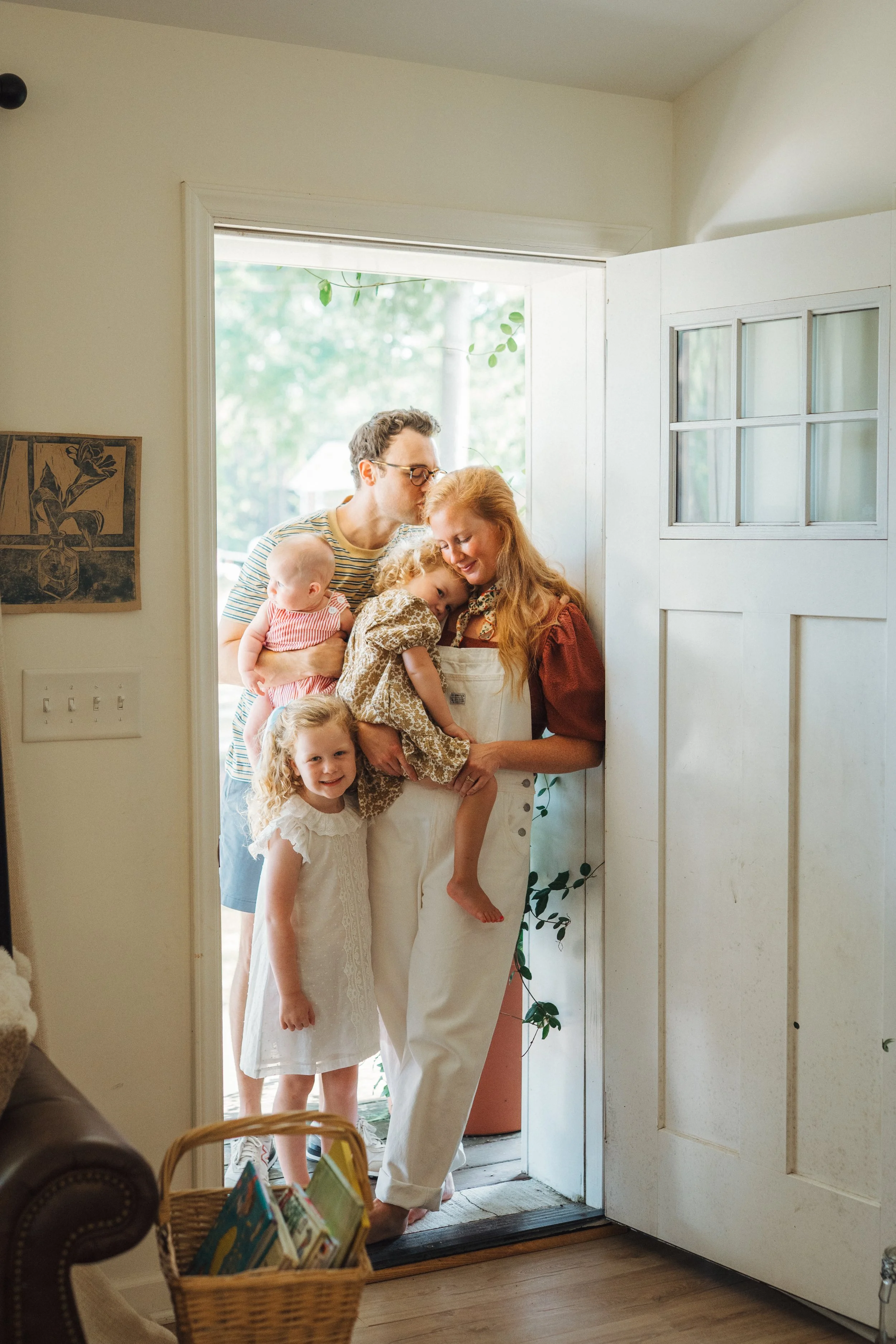 Family of five in Durham North Carolina home cuddled by their front door for lifestyle family photography