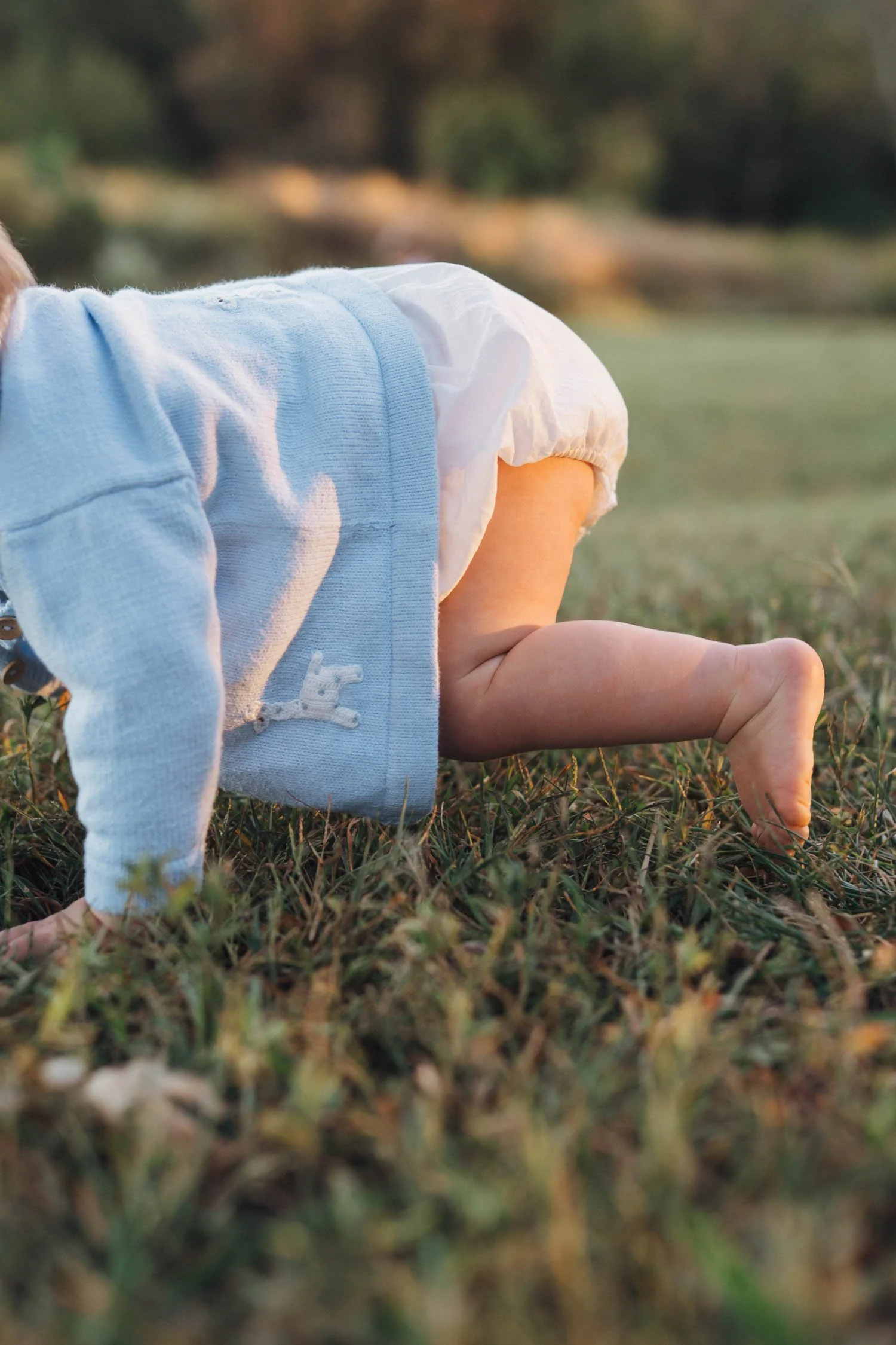 Close-up of a baby crawling through the grass outdoors during a natural family photography session in North Carolina.