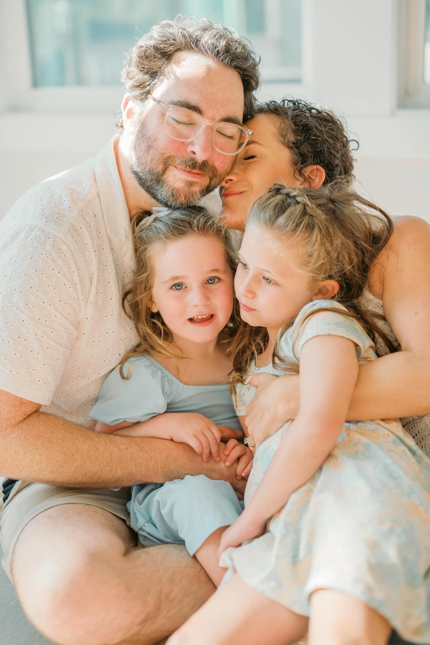 Family of four cuddling together inside their home during a relaxed family photography session in Raleigh, North Carolina.