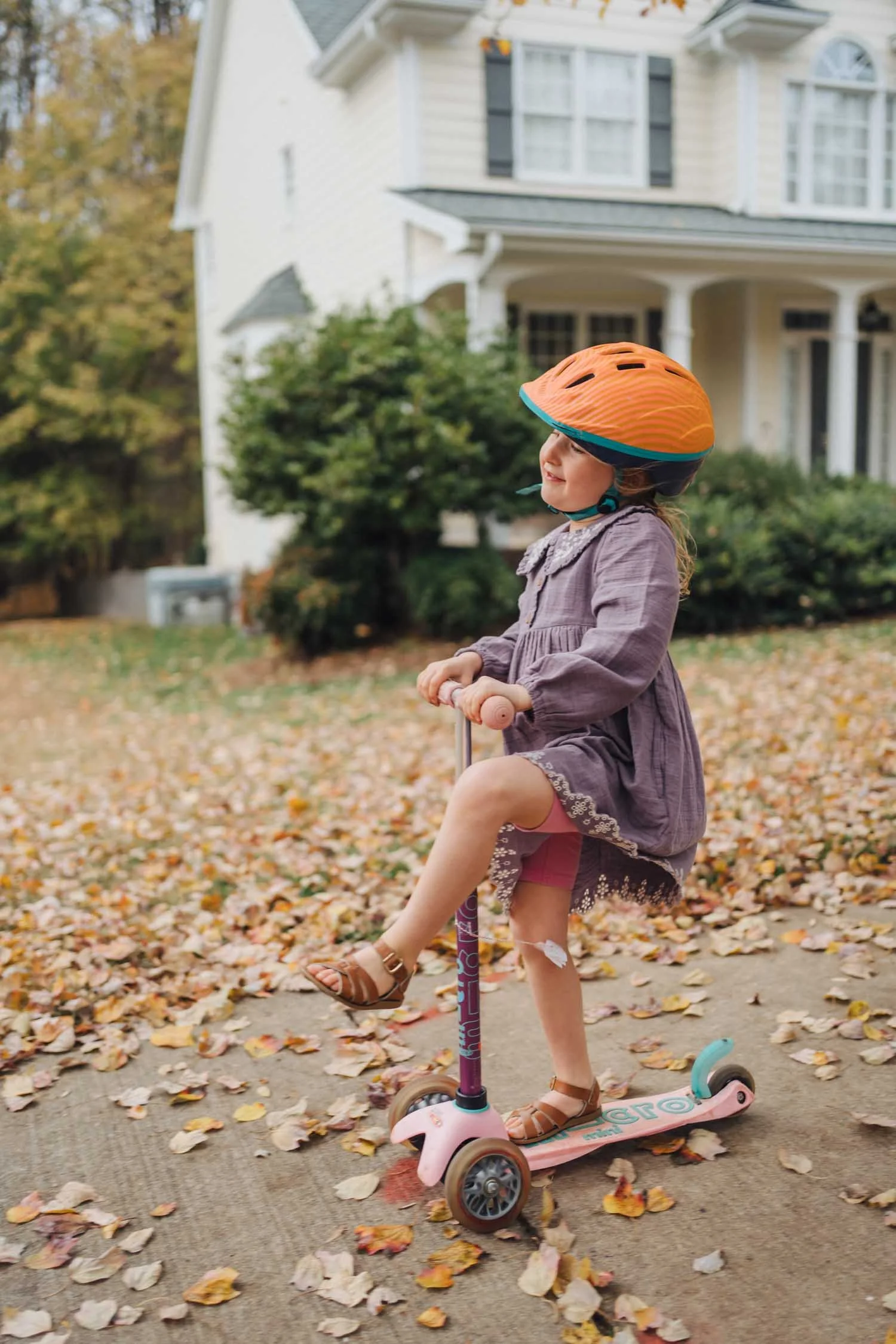 Child riding a scooter through the front yard during a playful family photography session in Raleigh–Durham.