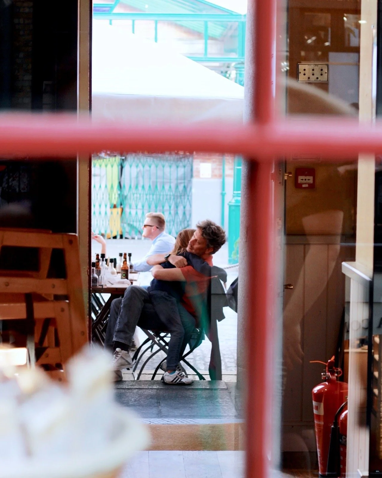 Photo seen through a window of a father holding his daughter, captured showcasing candid family photography.
