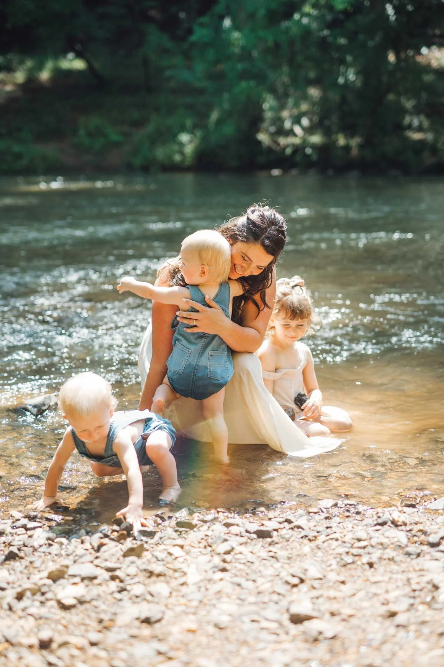 Mother and three young children splashing and playing in a local creek during a lifestyle family photography session in the Raleigh–Durham area.