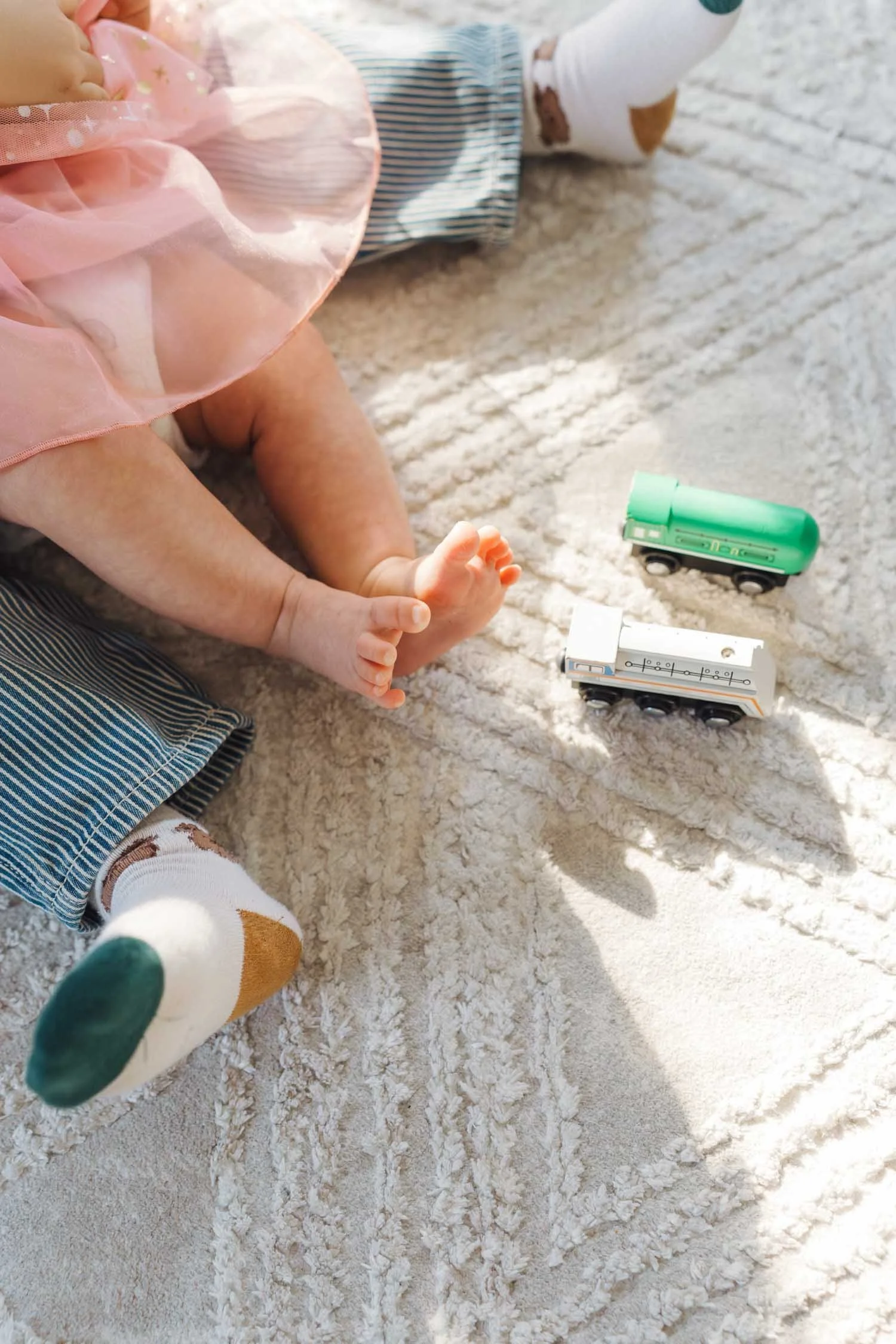 Close-up of a baby’s feet resting near toys on the floor during an in-home family photography session in Raleigh–Durham.